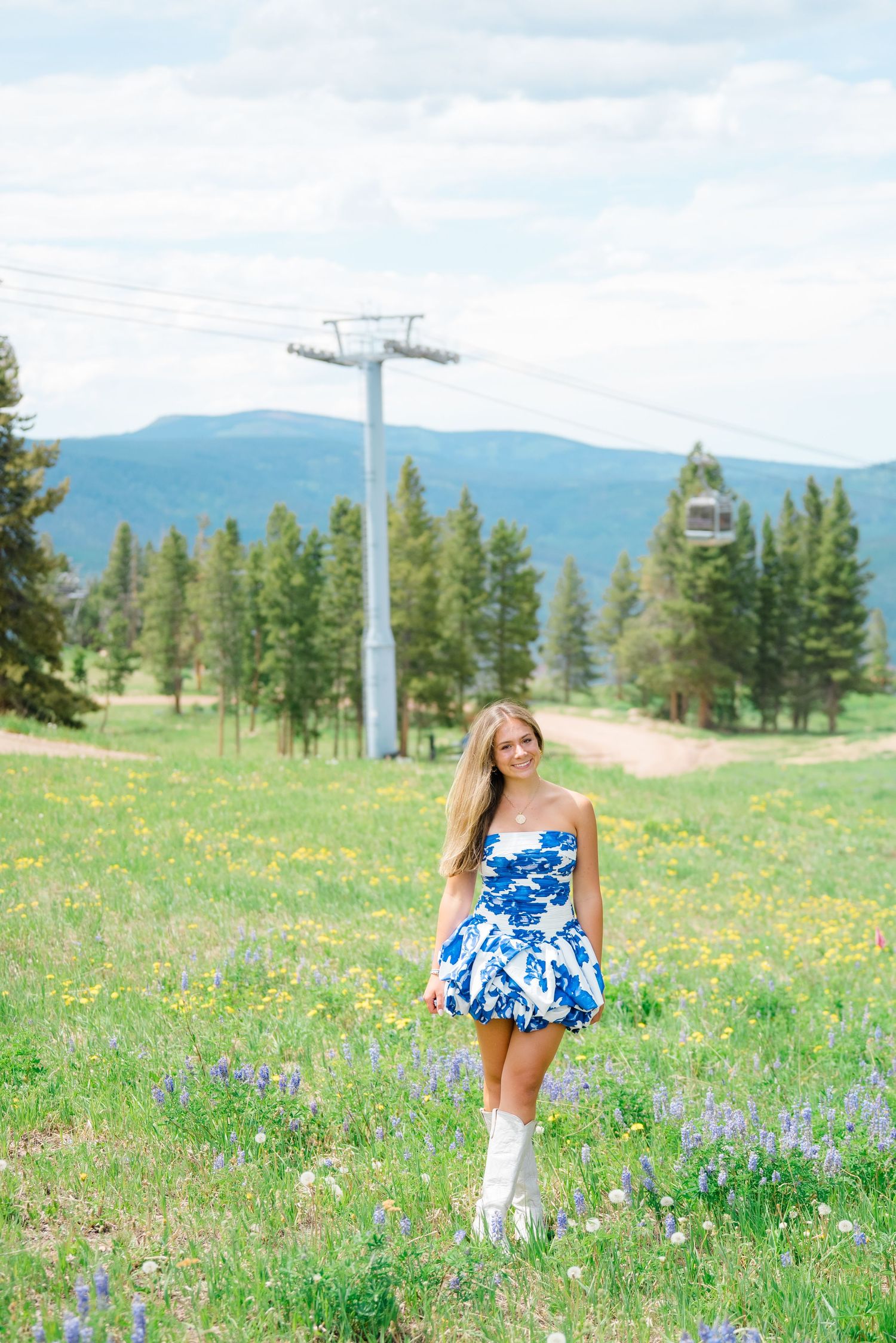 Blue floral dress in mountain meadow with ski lift and wildflowers during vail senior photography session.