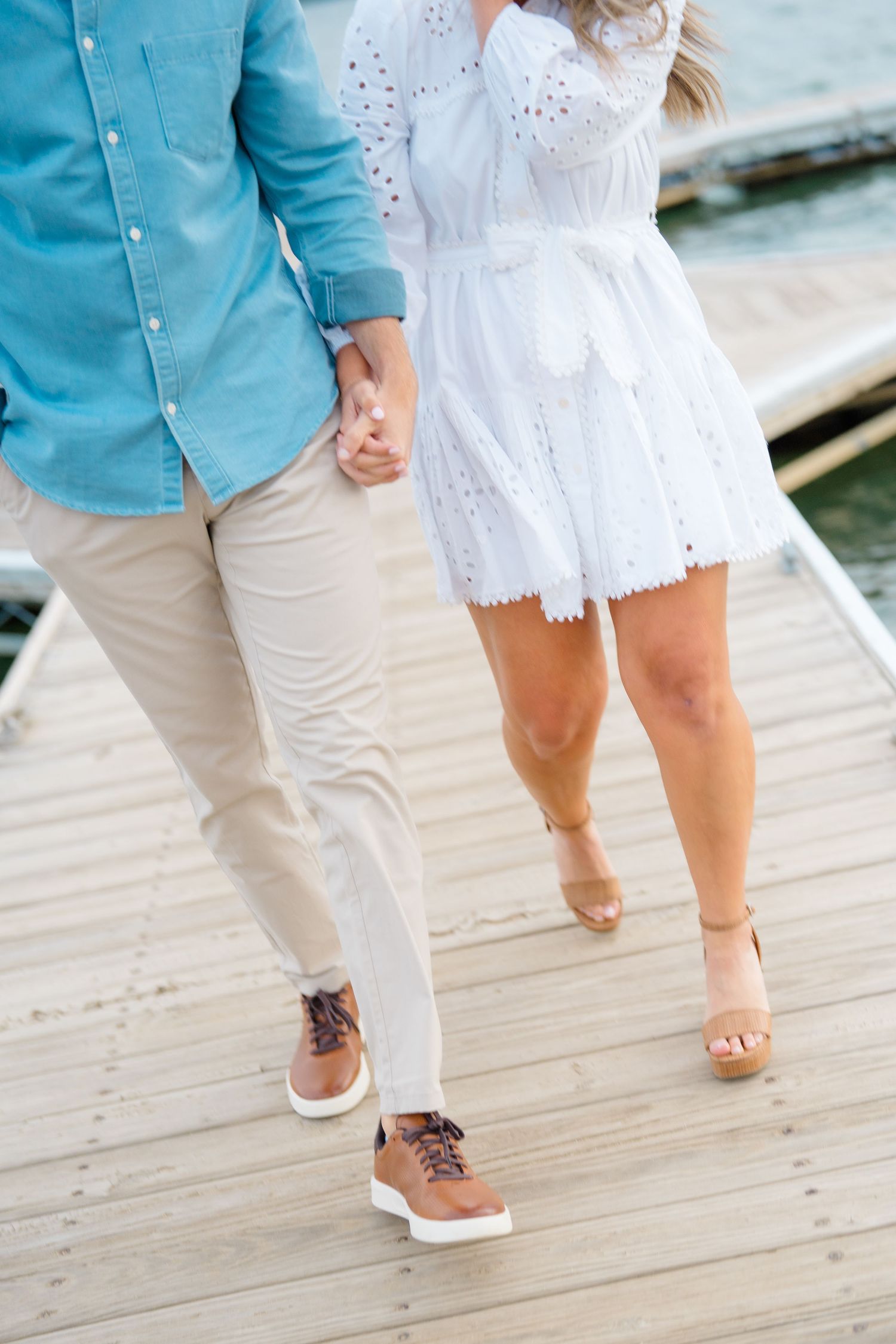 Close-up view of feet walking on a wooden dock showing white and teal summer outfits and casual footwear on lake dillon deck.
