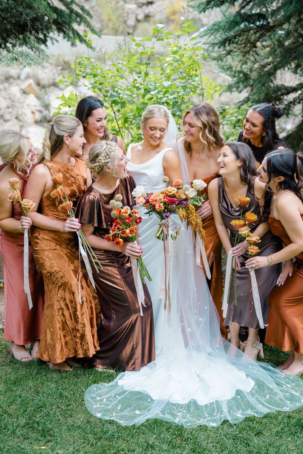 Smiling bride in a white gown and veil surrounded by bridesmaids at the Steamboat Springs wedding