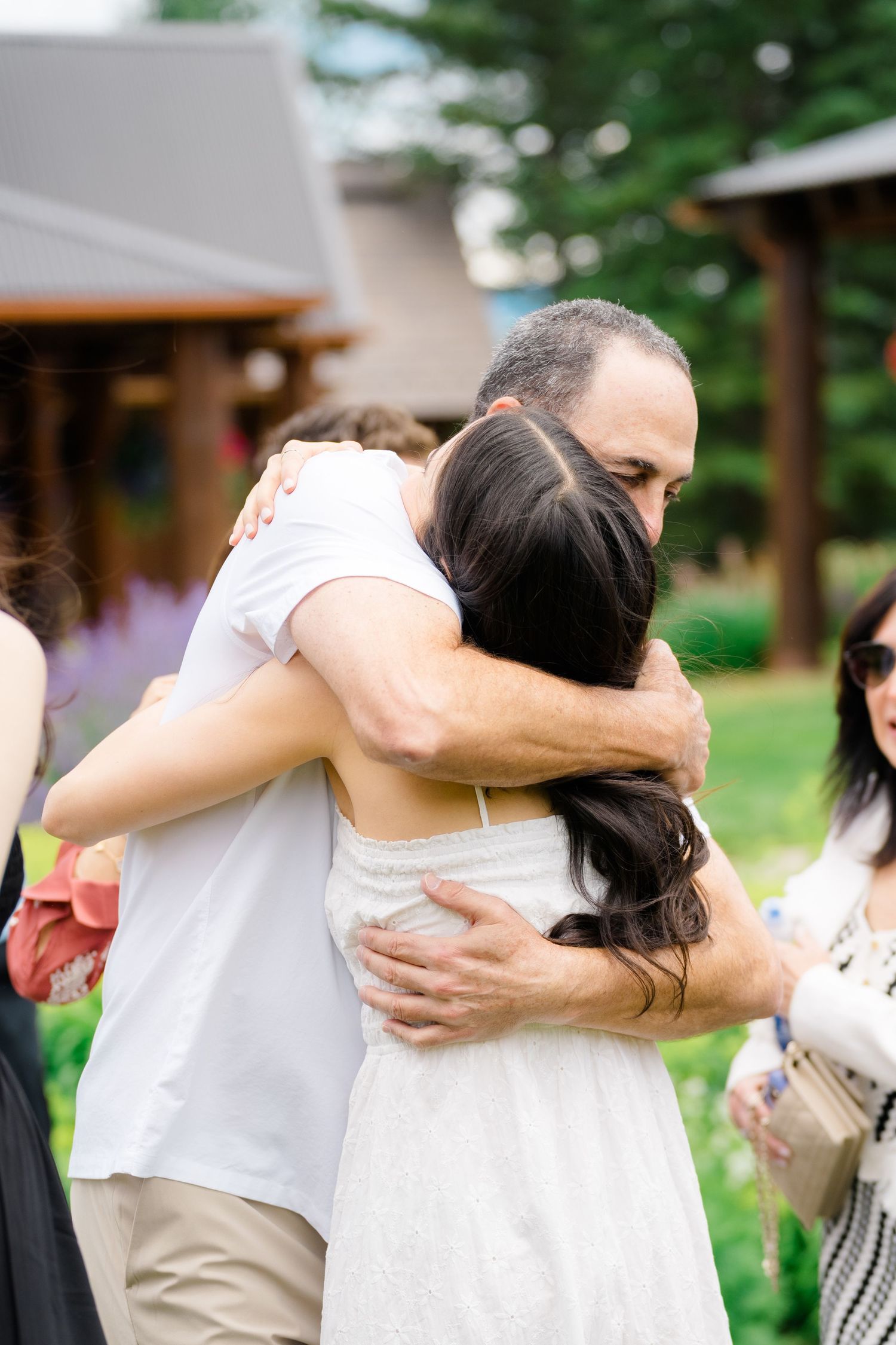 Group of people sharing emotional embraces at an outdoor gathering.