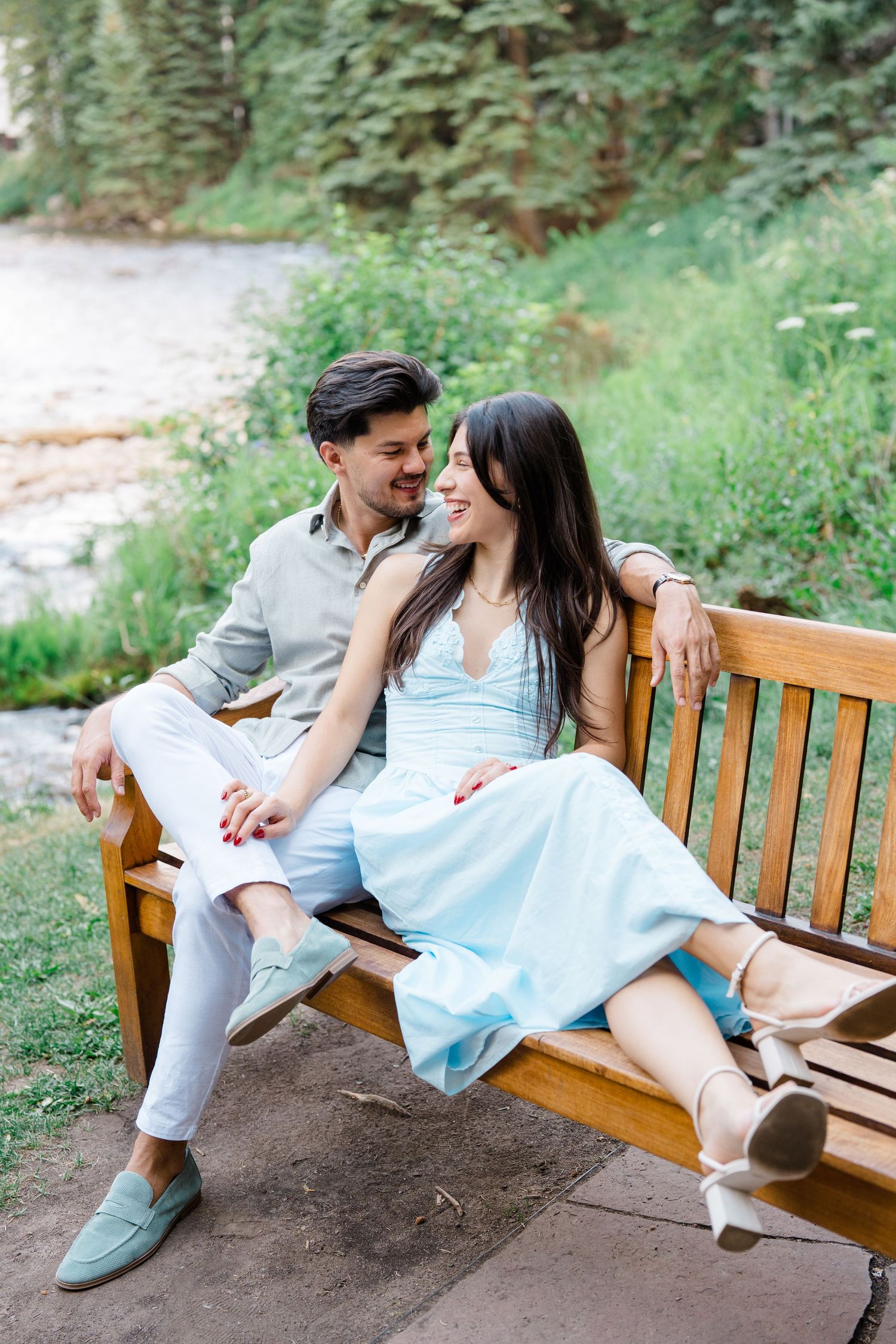 guy and girl talking and smiling on a bench in vail village after their proposal