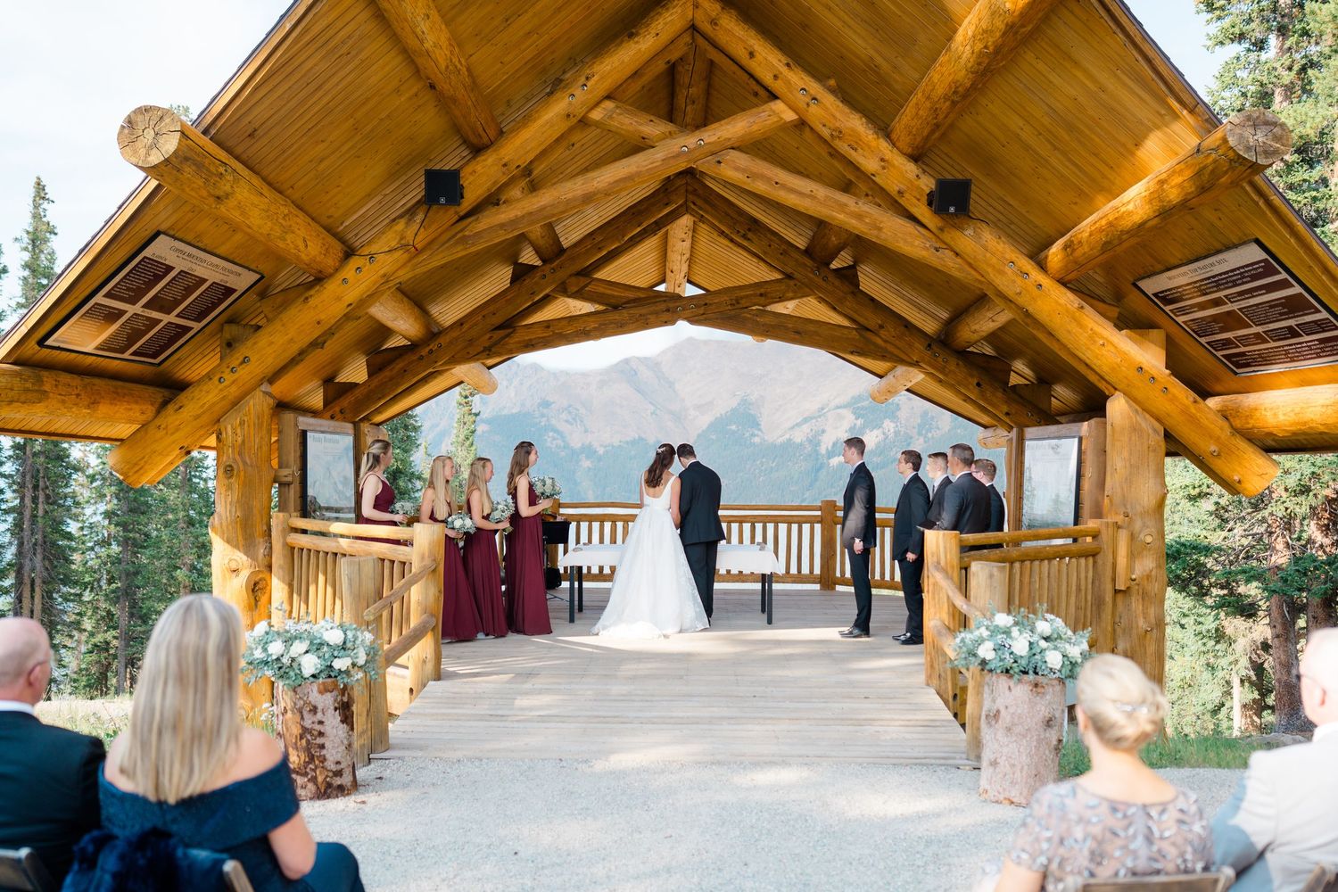Wedding ceremony taking place under a rustic wooden pavilion with mountain views in the background at copper mountain.
