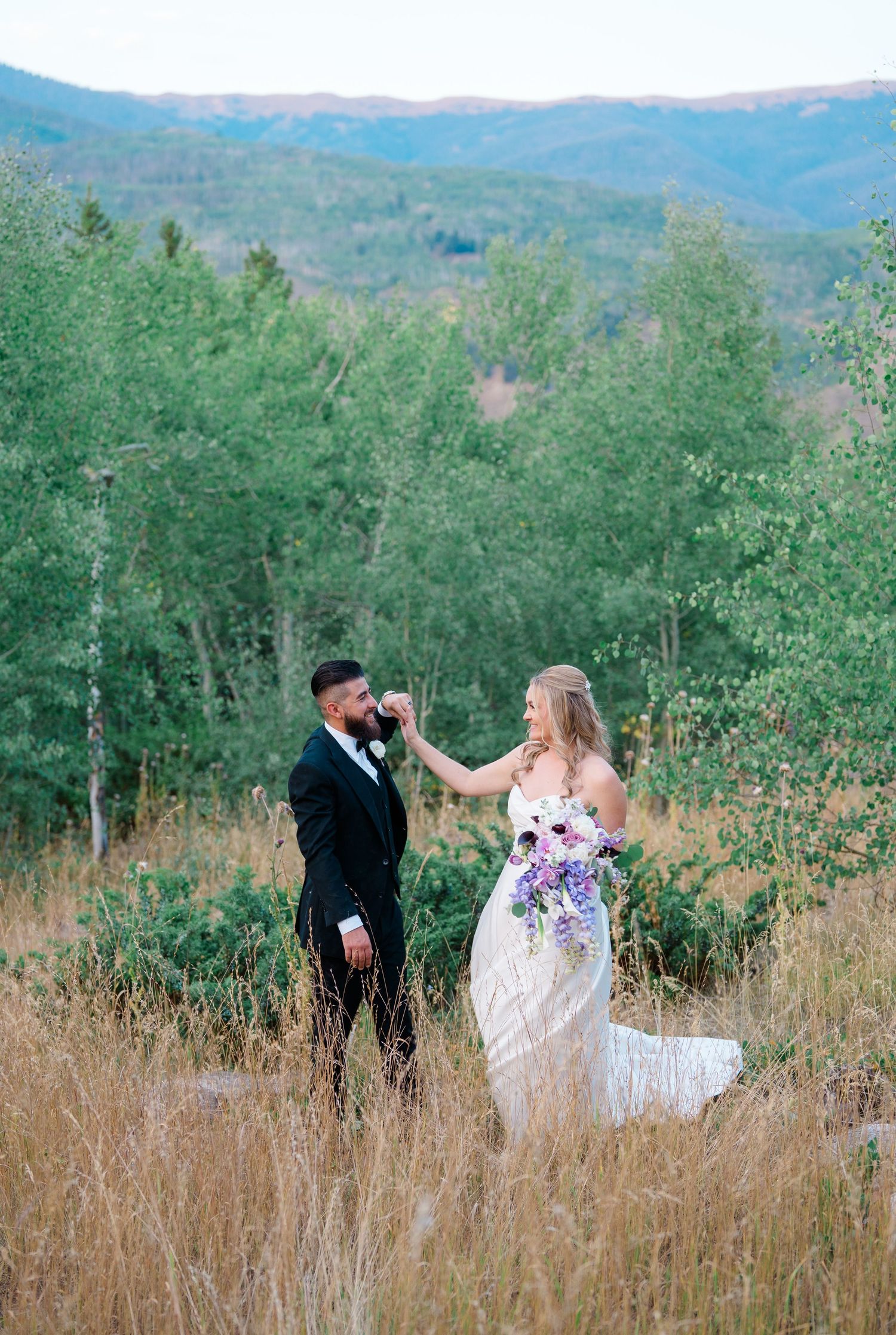 A couple shares romantic moments in a mountain meadow surrounded by aspen trees and tall grass on their Breckenridge wedding day.