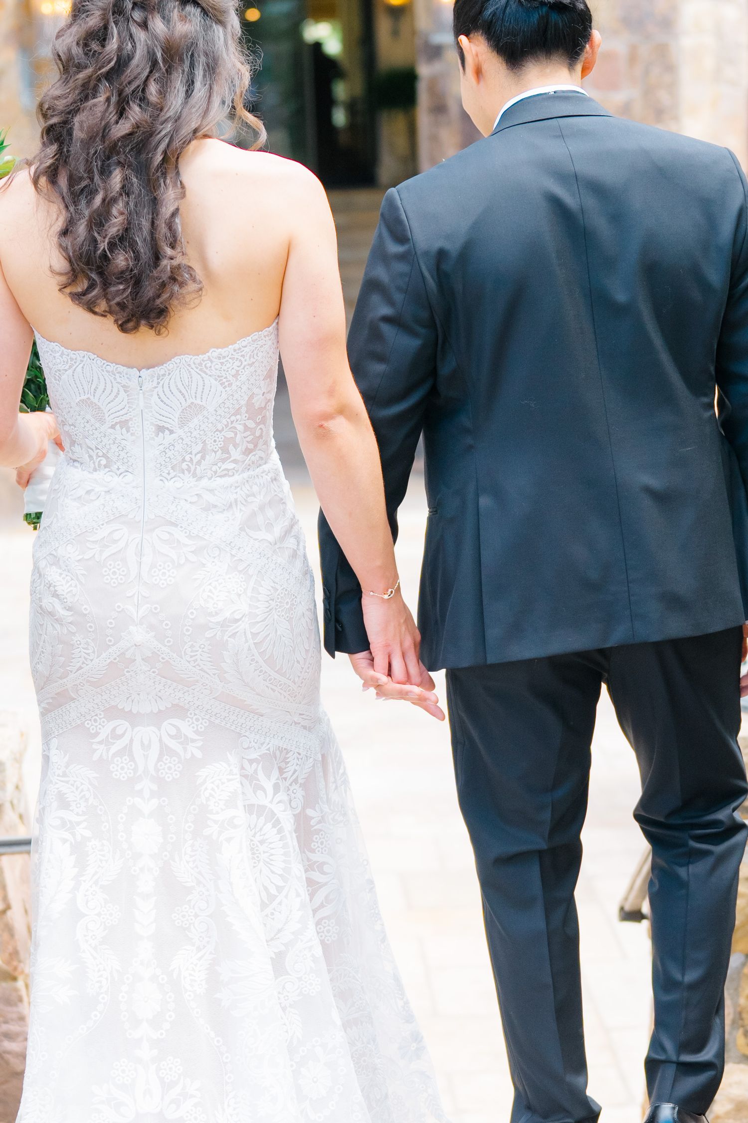Wedding party members in black suits and white dresses walk together in a line during a formal celebration.