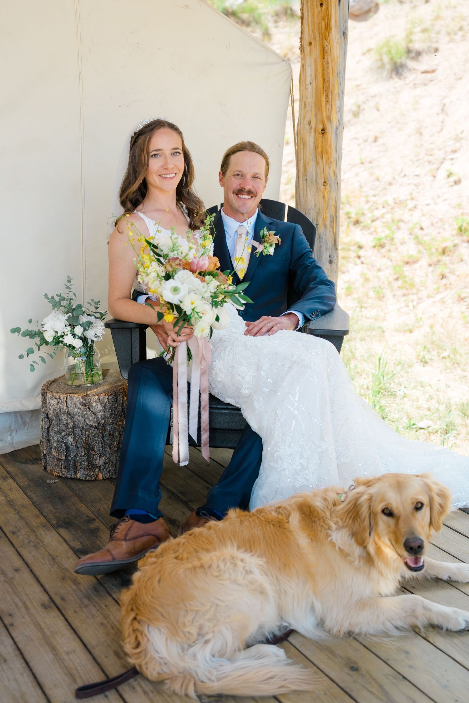 A wedding party poses on a rustic wooden porch with a friendly golden retriever lounging in front at Piney River Ranch Wedding.