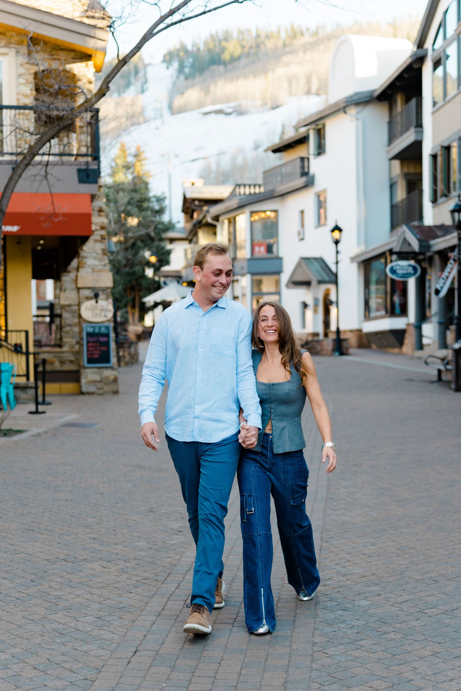 A couple walks and laughs together along a charming European-style village street.