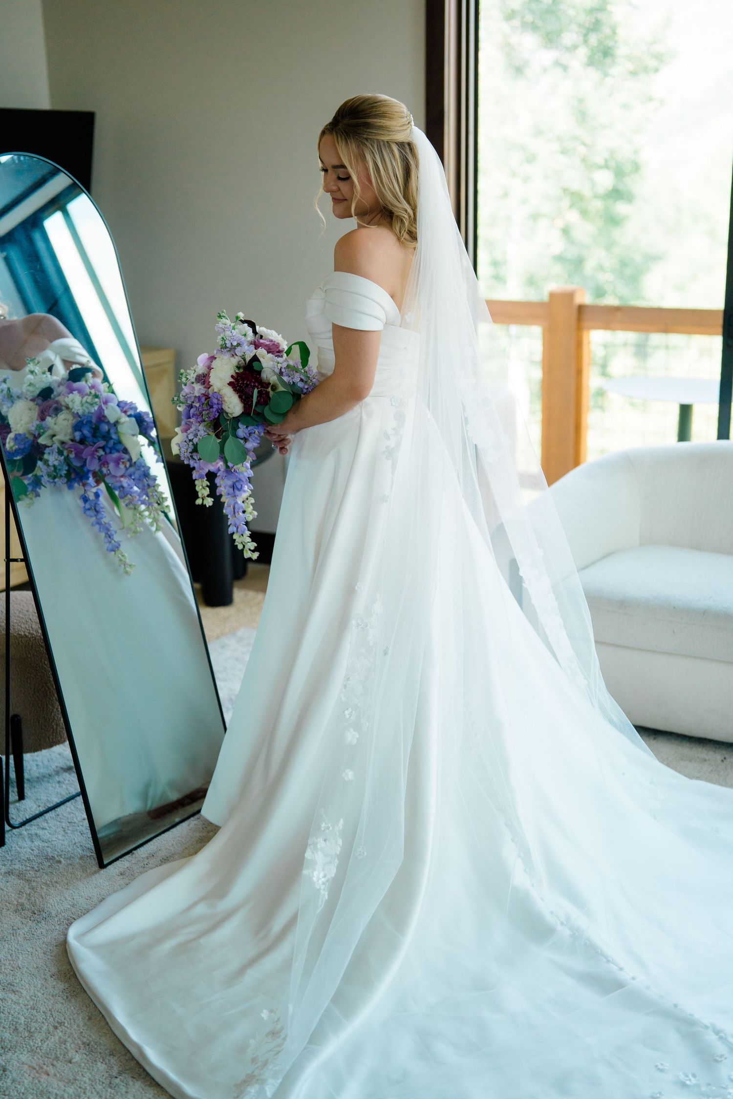Wedding dress details with flowing white fabric and purple floral bouquet arrangements.