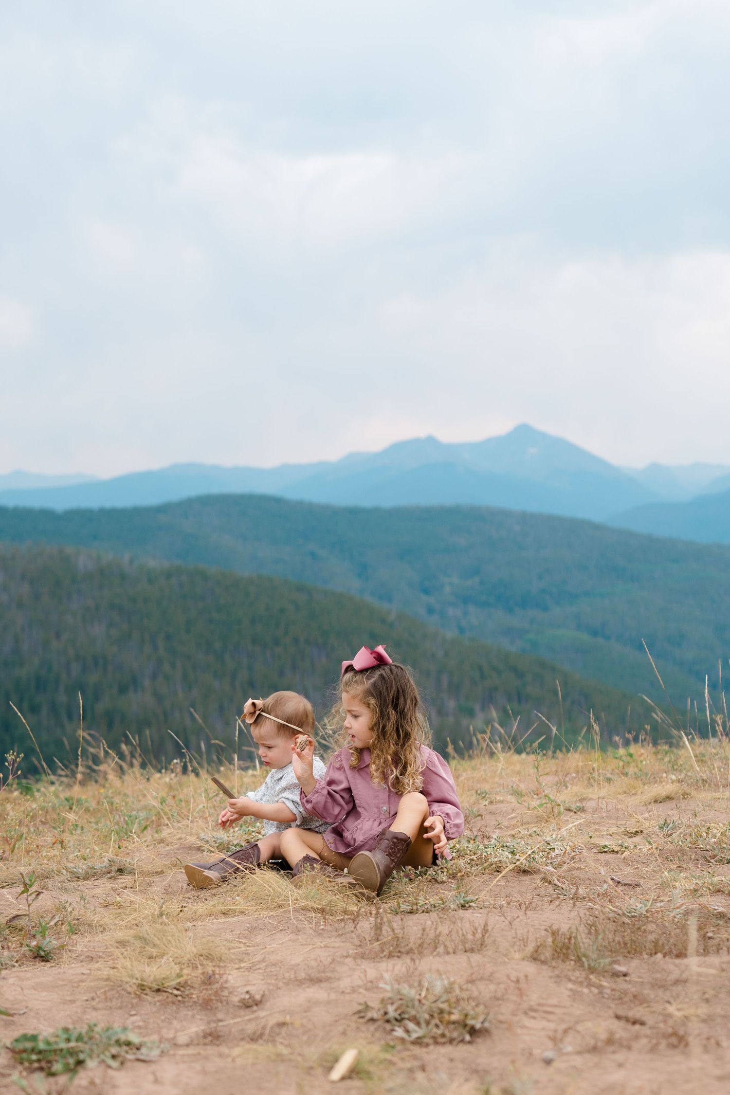 Children lying on mountain trail looking at scenic mountain vista during vail family photography session.