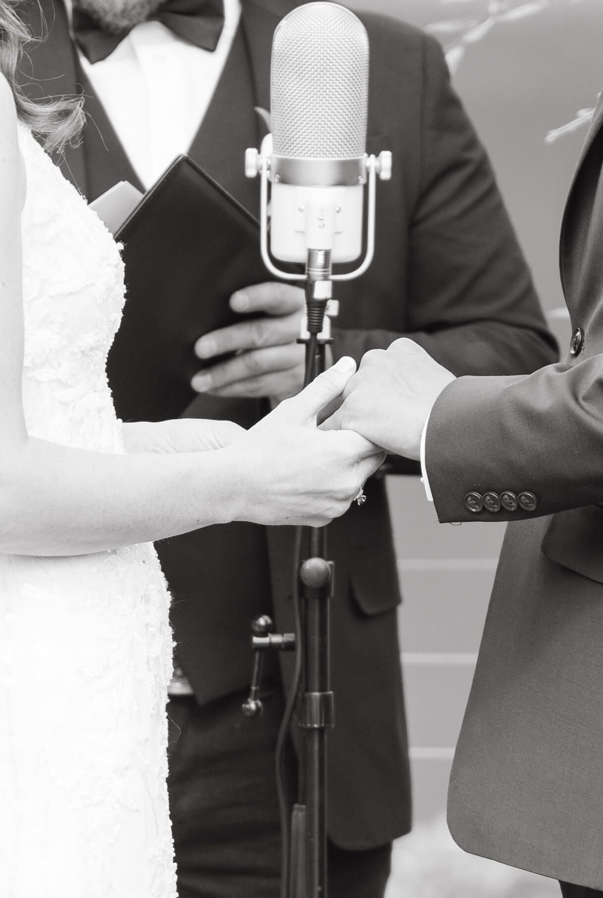 Black and white photo of bride and groom exchanging rings at wedding ceremony at Piney River Ranch Wedding.