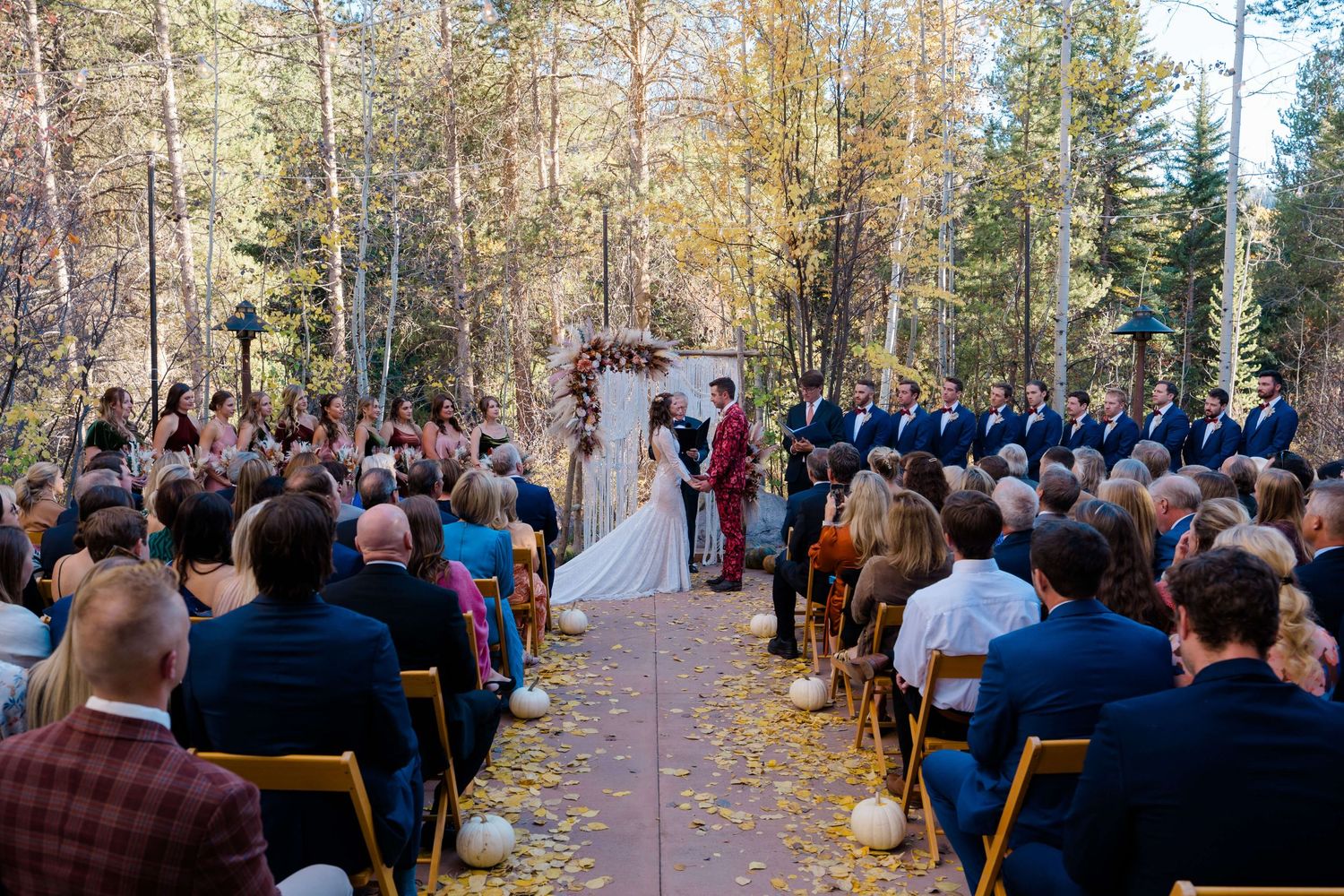 Outdoor fall wedding ceremony in a forest out back at Donovan Pavillion Vail Wedding Venue.