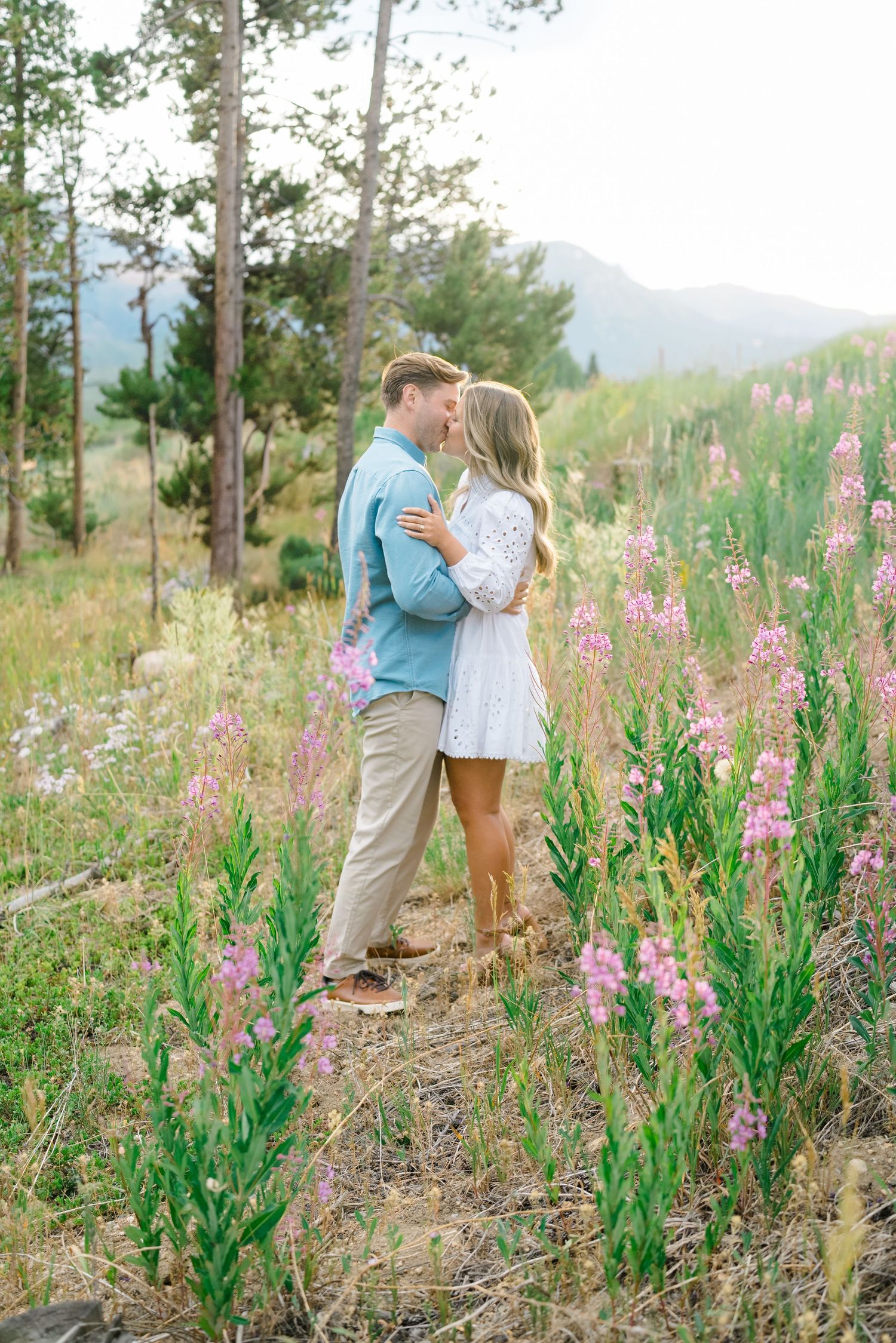 A couple embraces among pink wildflowers in a mountain meadow during a romantic outdoor photo session at lake dillon.