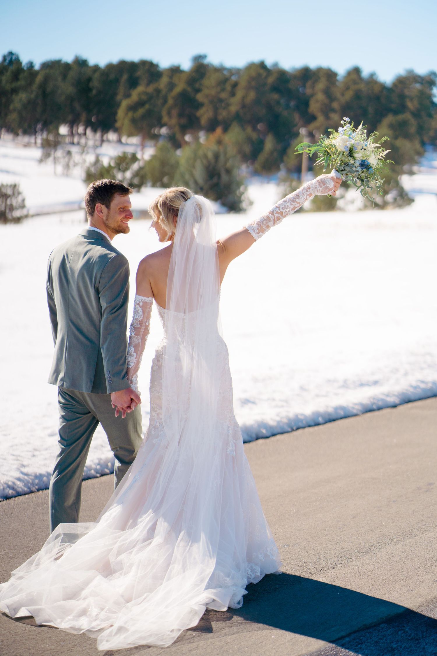 Wedding couple walking along snowy path with flowing white dress and veil captured by Vail Wedding Photographer.