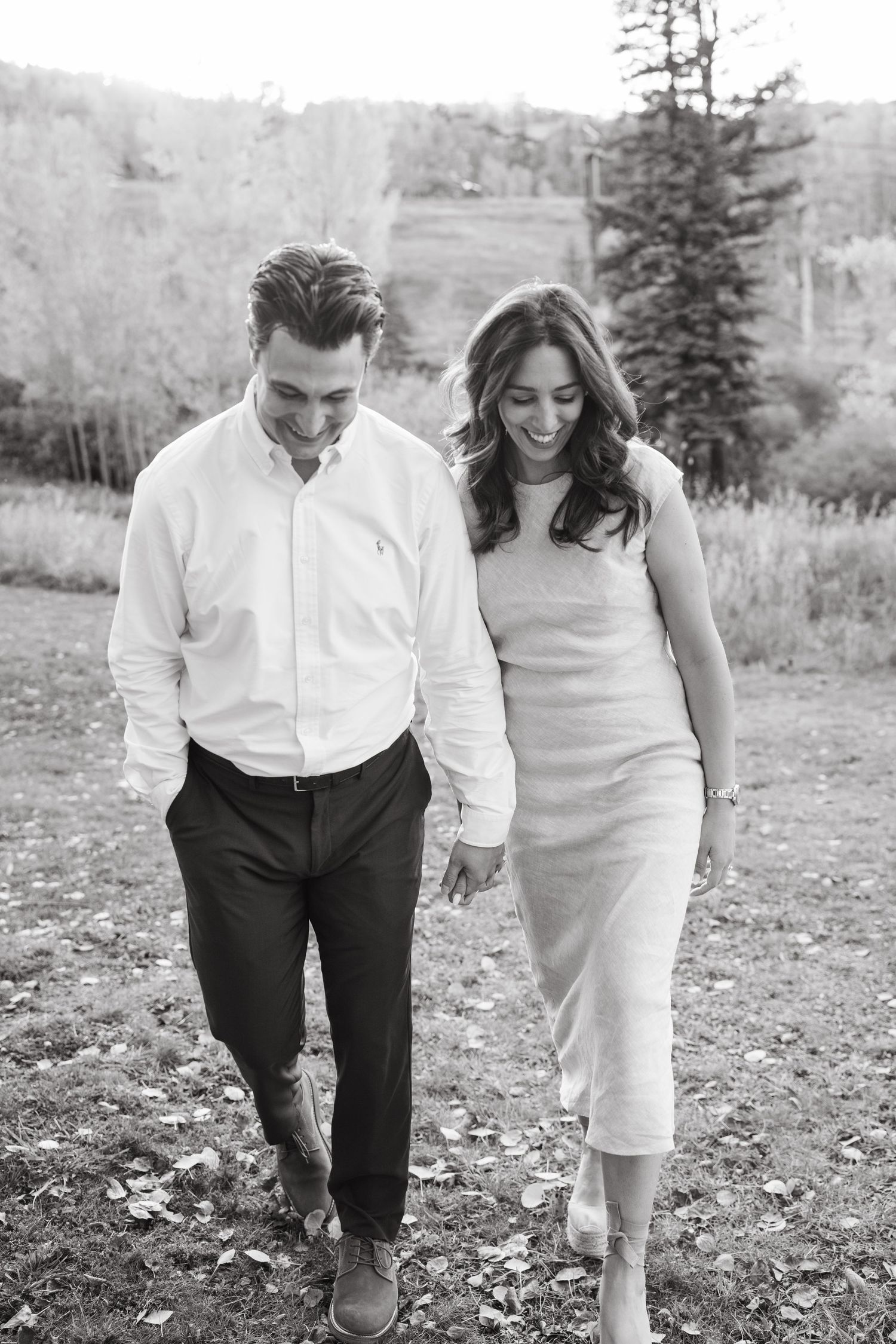 A romantic black and white photo of a couple walking together outdoors in elegant attire.