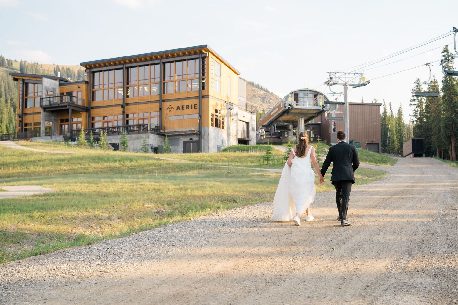 A couple walks along a rustic dirt path near a wooden building on a sunny autumn day at aerie copper mountain
