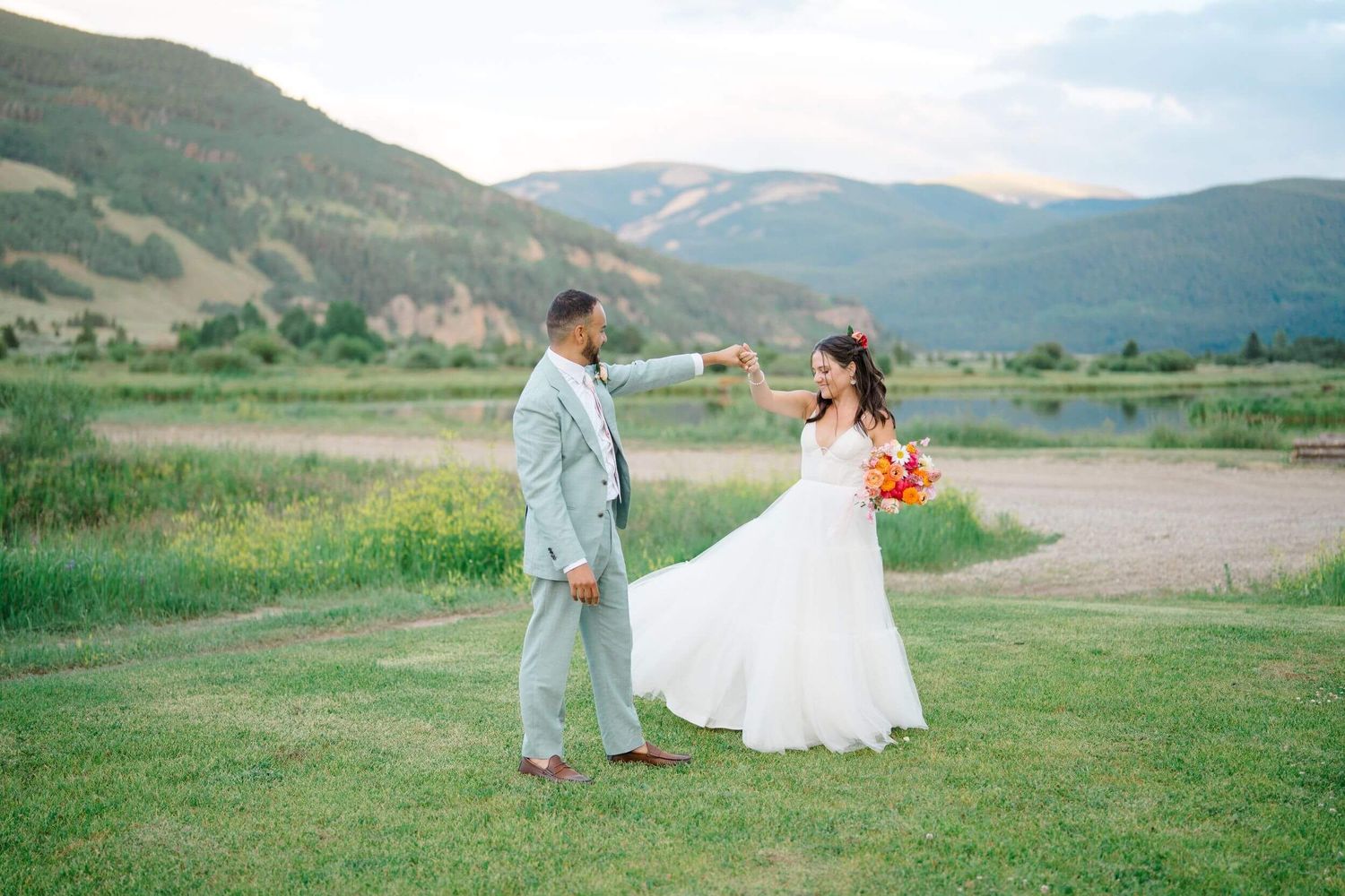 Camp Hale Wedding couple walking through a meadow with scenic mountain views in the background.