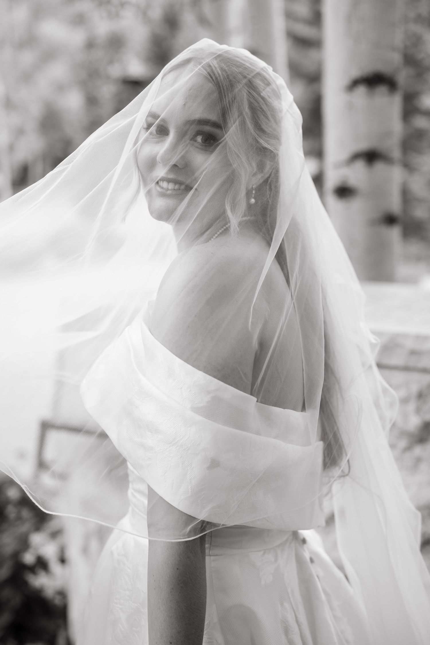 A close-up series of a bride with flowing veil captured in ethereal black and white photography.