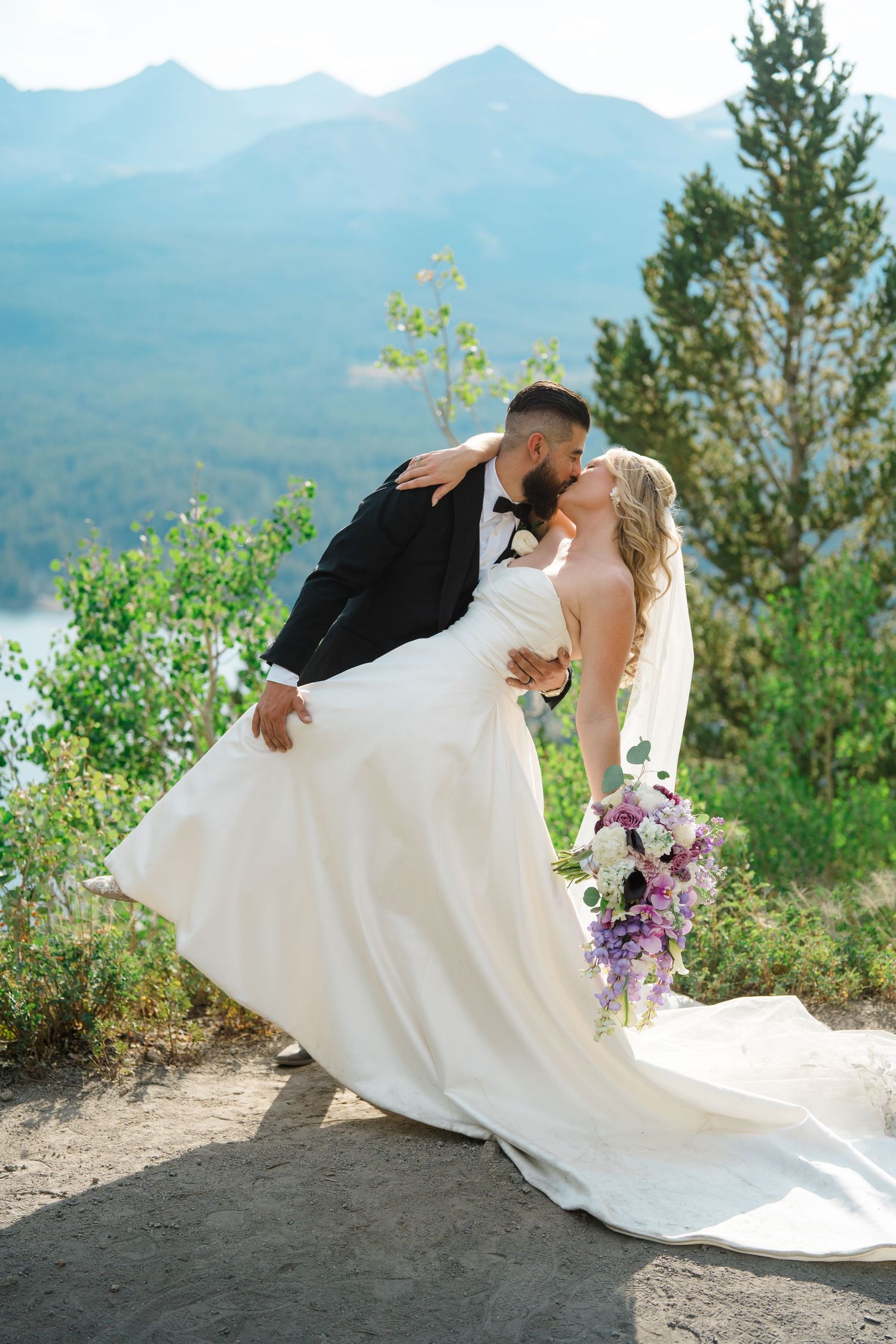 A romantic wedding photo series showing a couple in a dramatic dip pose against a mountainous backdrop.