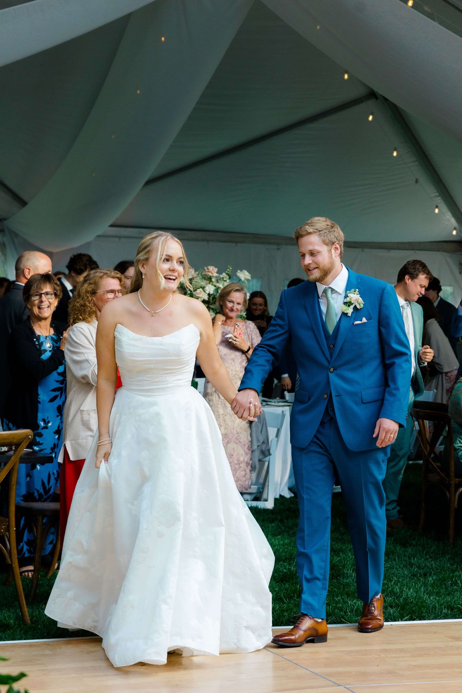 Wedding party dancing and celebrating on a wooden dance floor under a white tent during an outdoor reception during vail wedding.
