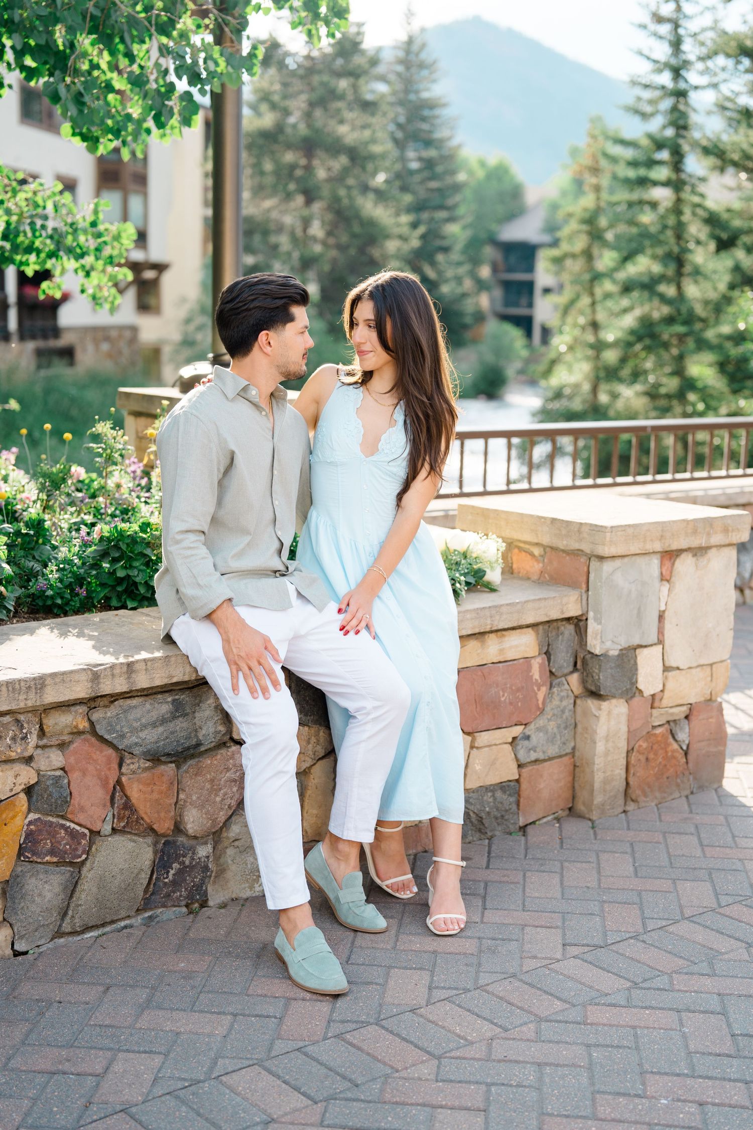 guy and girl sitting in vail village smiling after each other during engagement session.