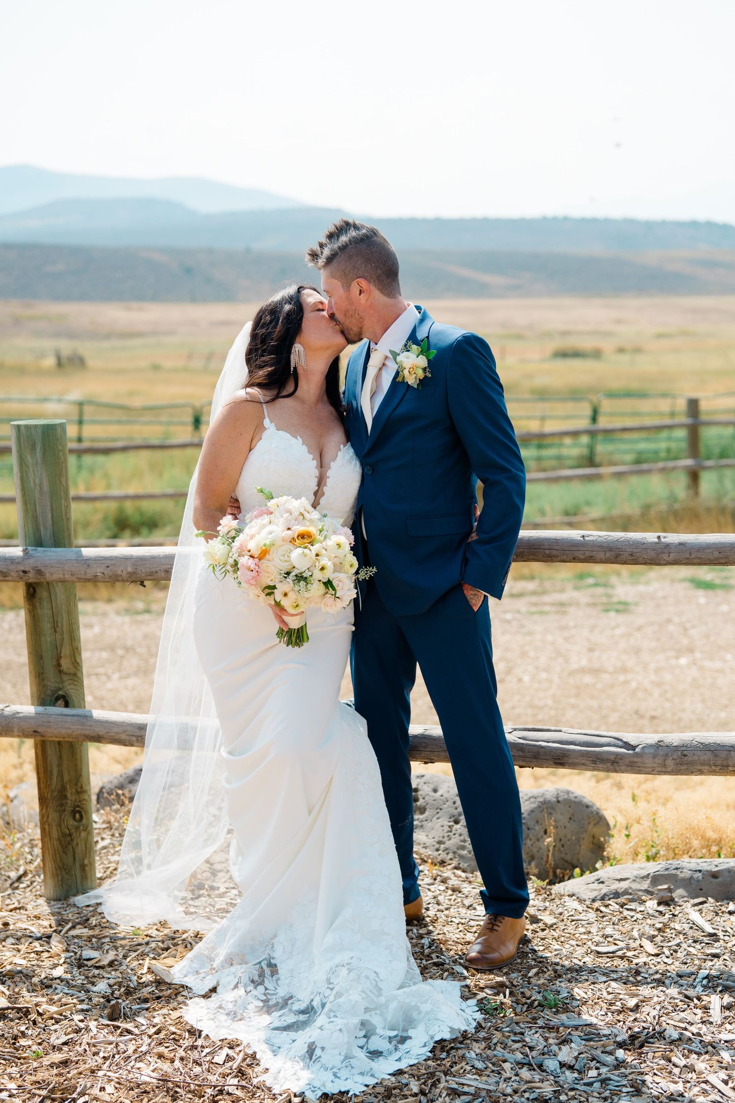 A romantic moment captured at a rustic ranch with mountain views in the background.