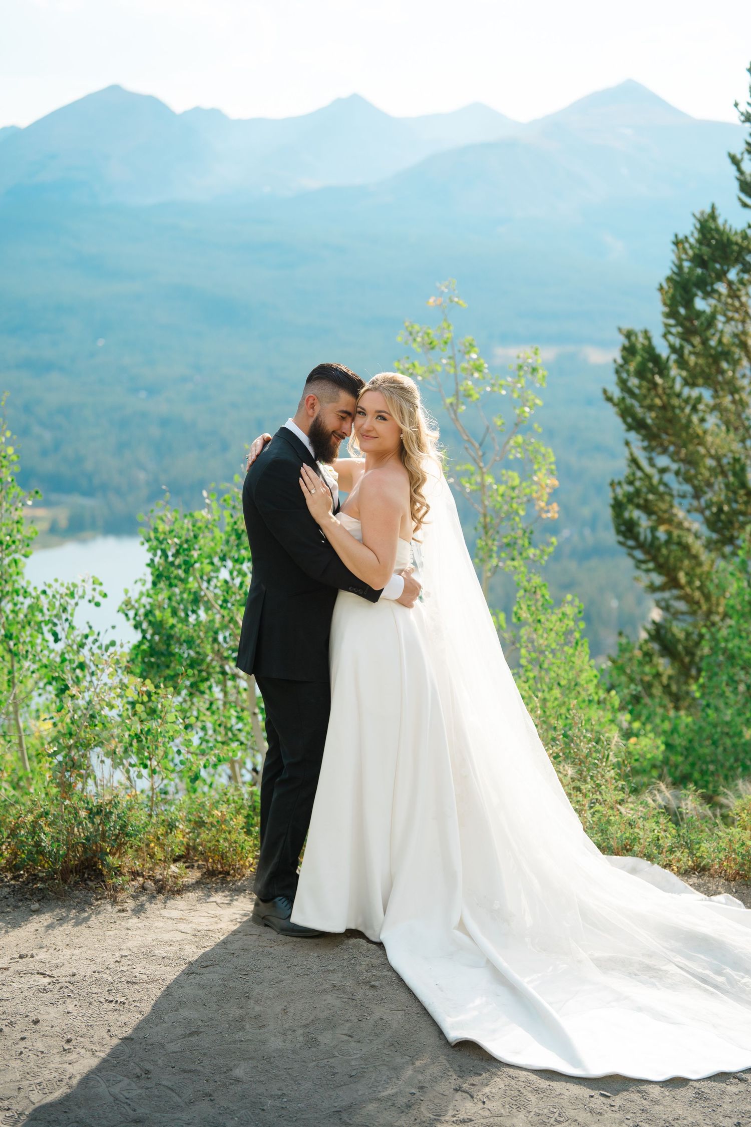 A romantic wedding couple shares an intimate moment overlooking a scenic mountain lake landscape during Breckenridge micro wedding.