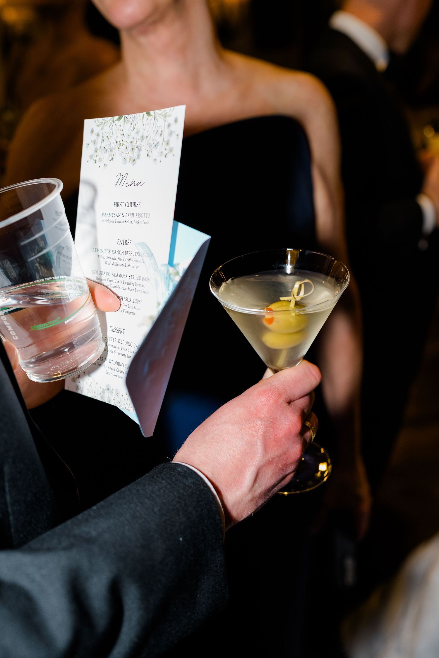 Person holding a dirty martini with olives and a wedding menu card at a formal event at Vail Sonnenalp Wedding.
