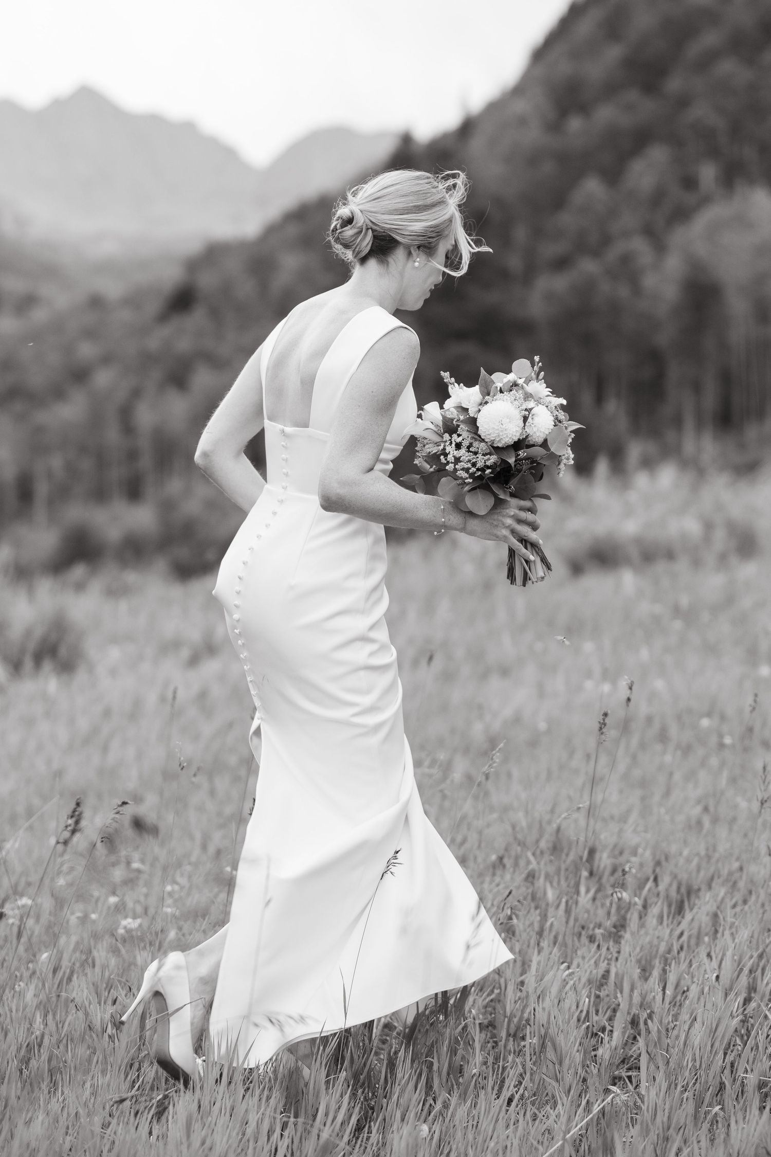 Black and white sequence of a bride in a white dress twirling joyfully in a meadow with mountains in the background in vail wedding.