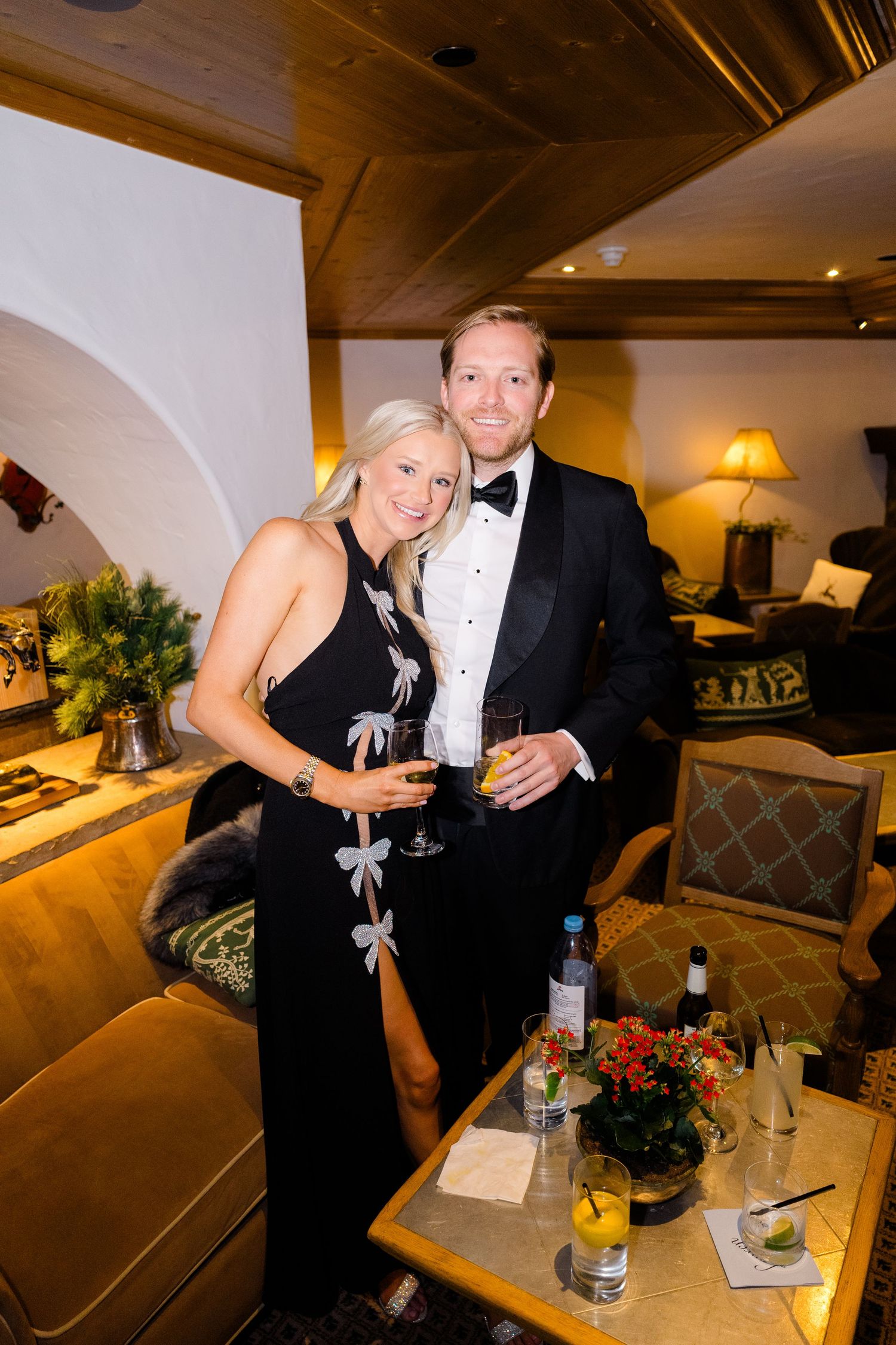 Elegant couple in formal attire holding drinks at an upscale event, woman in black gown, man in tuxedo at Vail Sonnenalp Wedding.