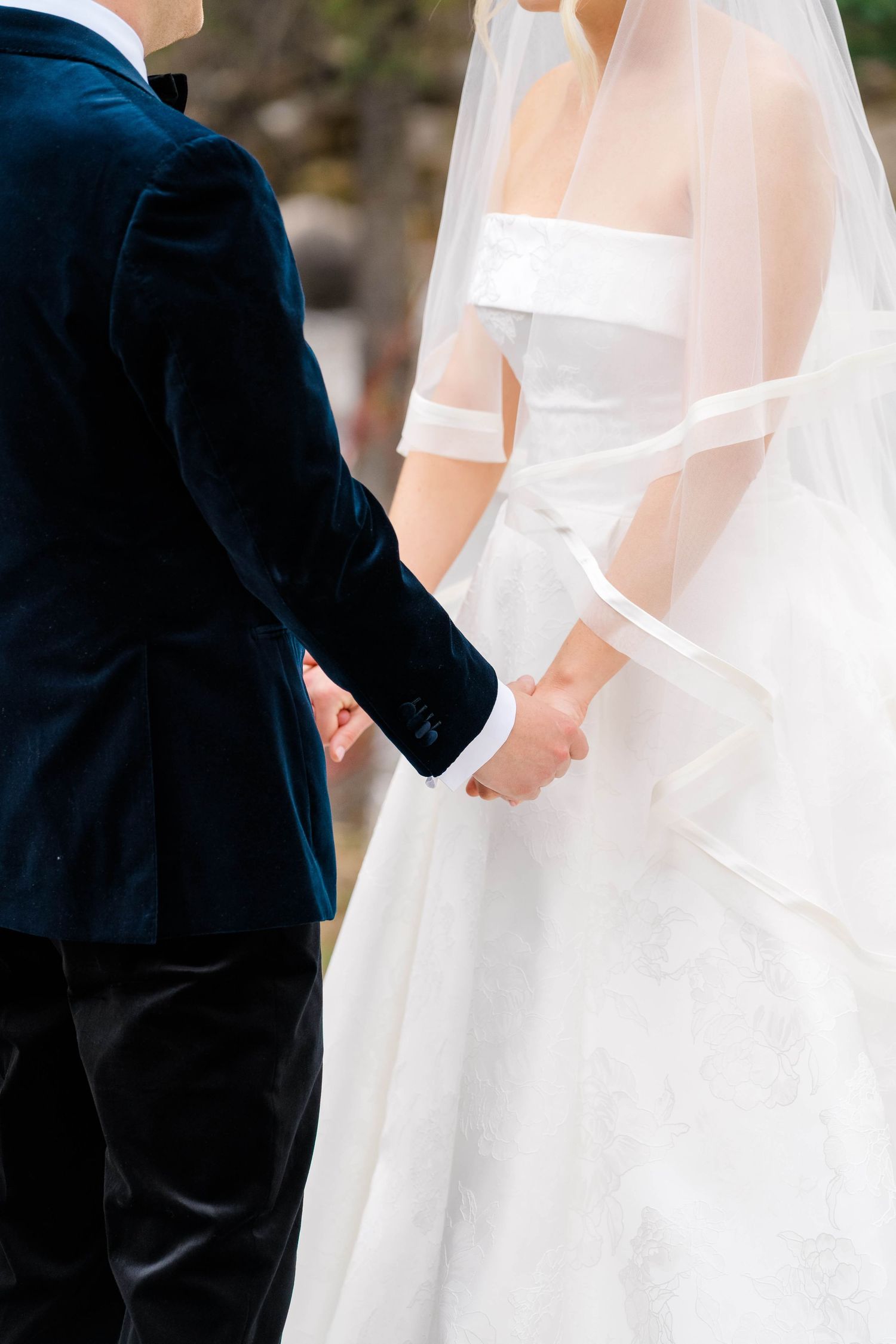 Bride and groom holding hands, wearing white wedding gown with veil and navy blue velvet suit at Vail Sonnenalp Wedding.