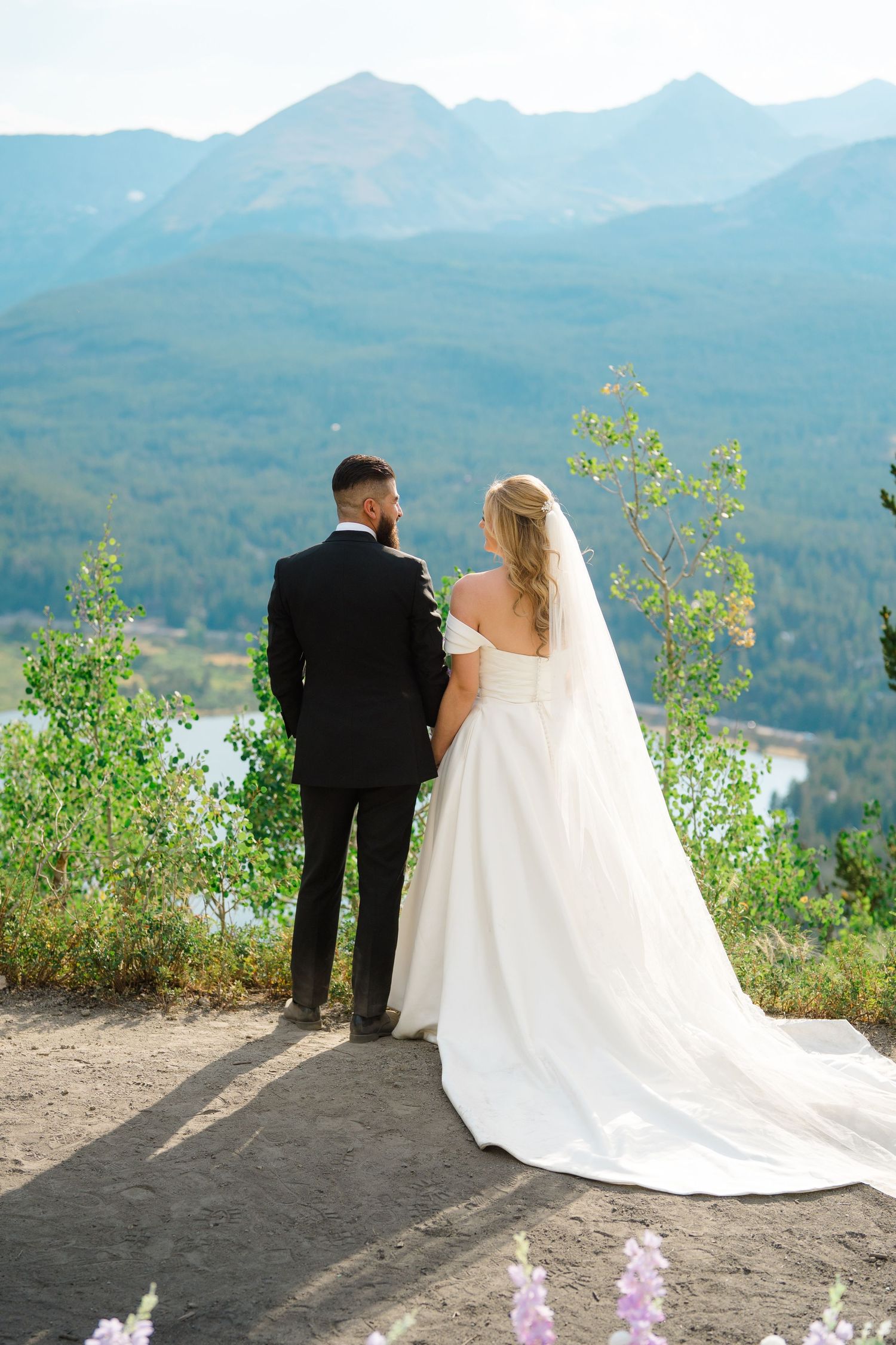A couple stands on a mountain overlook with a scenic lake and mountain vista in the background during Breckenridge micro wedding.