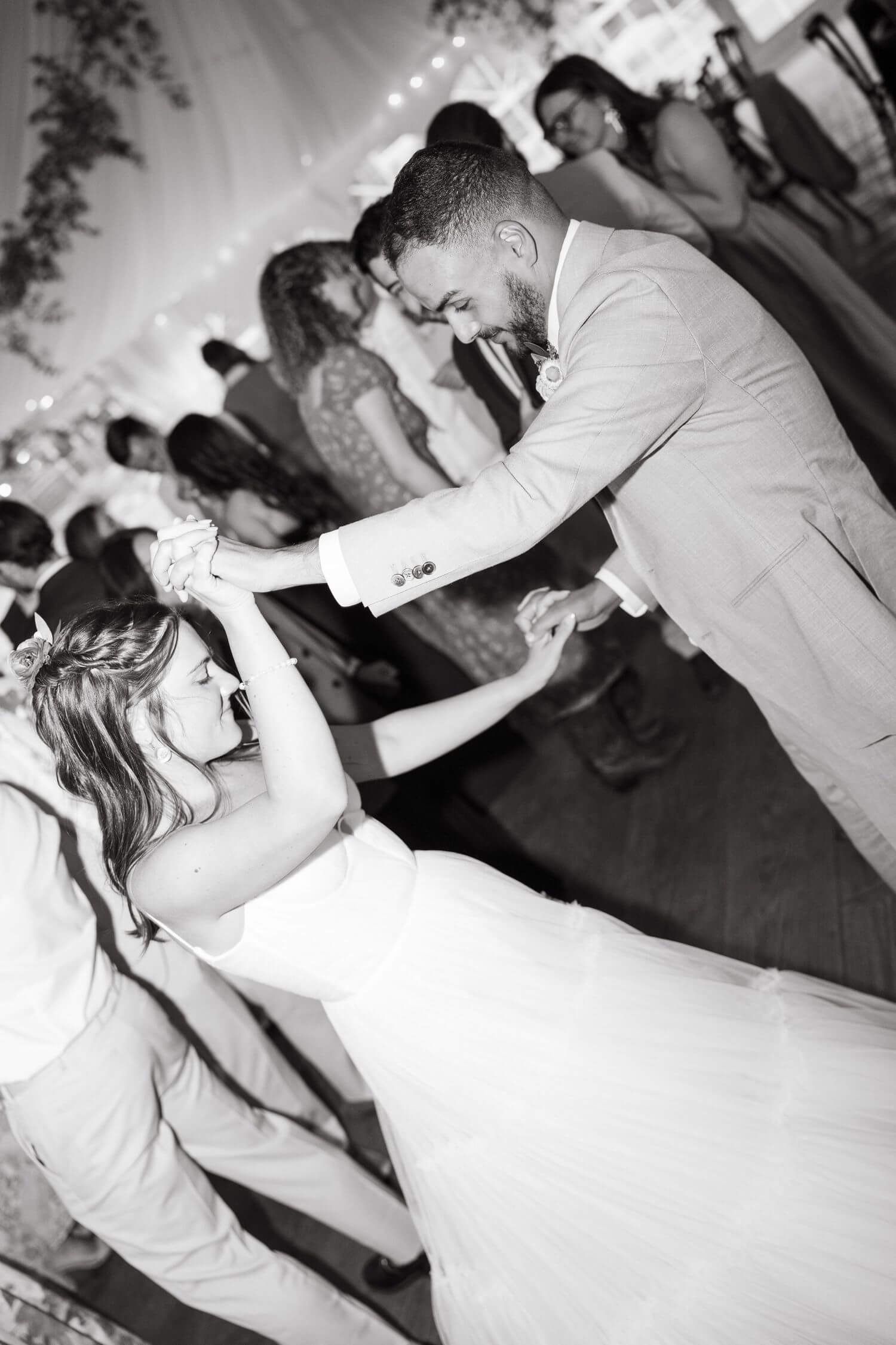 A couple shares an energetic dance moment at their camp hale wedding reception in black and white photography.