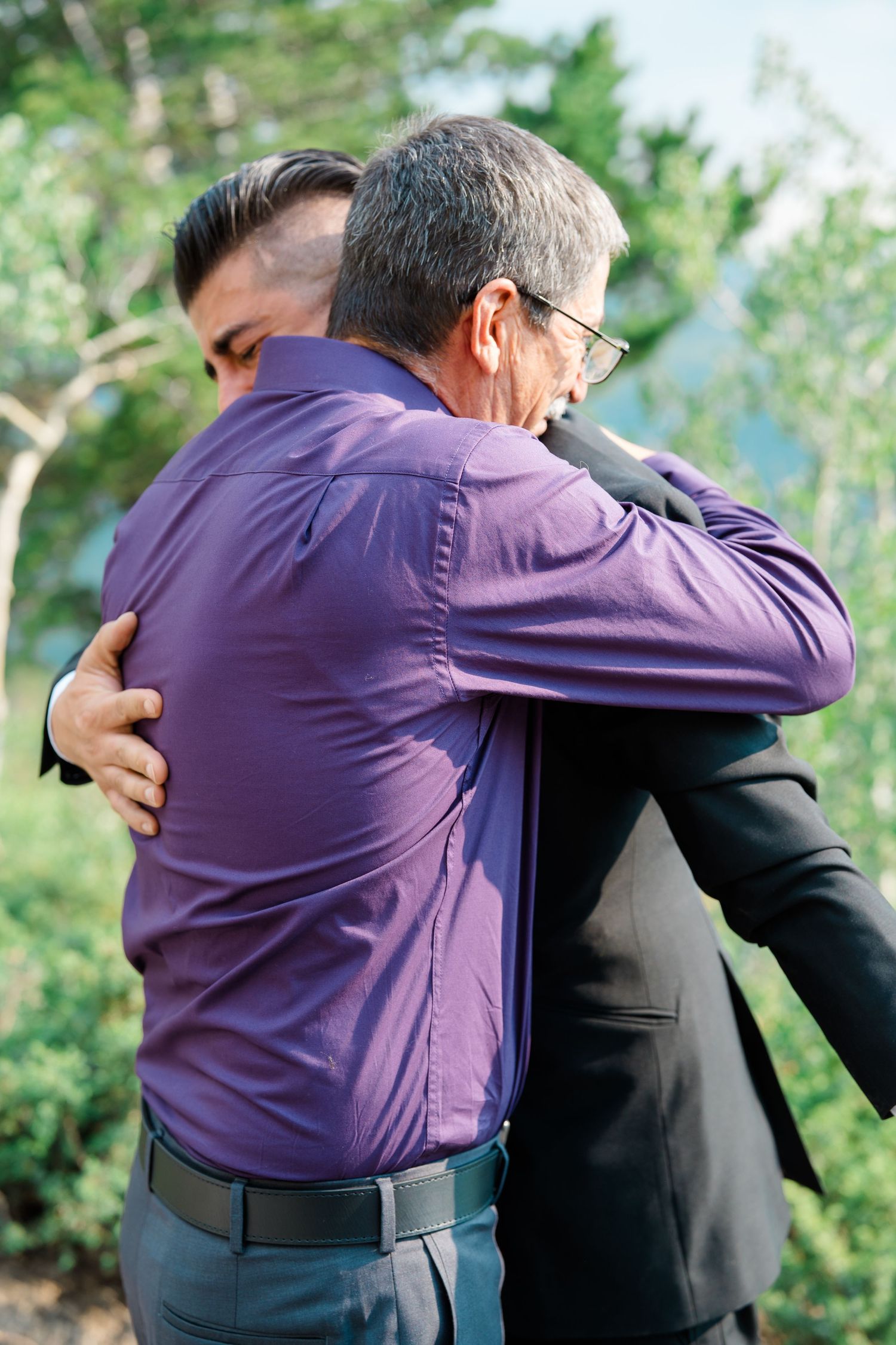 Two people share an emotional embrace during an outdoor wedding ceremony in the mountains.