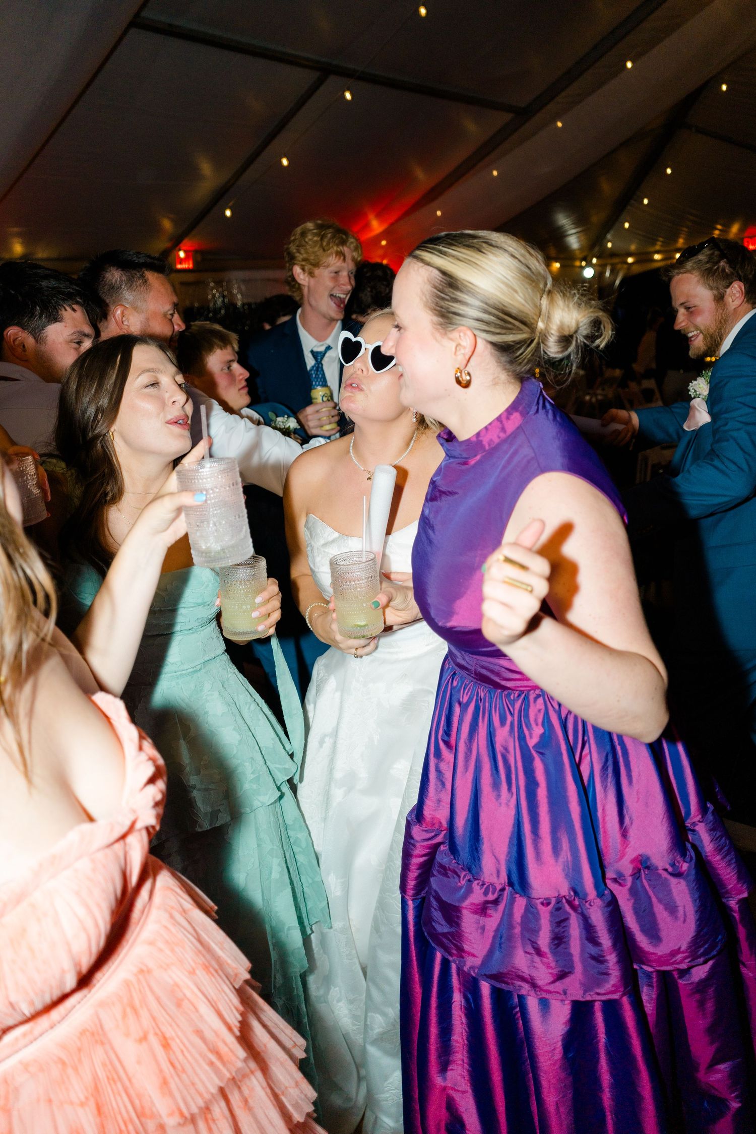 Wedding guests dancing and celebrating at a lively reception with colorful dresses and party atmosphere.