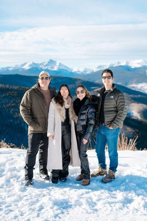 Best vail family photo locations - group enjoying a winter day together in the snowy mountains with snow-capped peaks and blue skies.