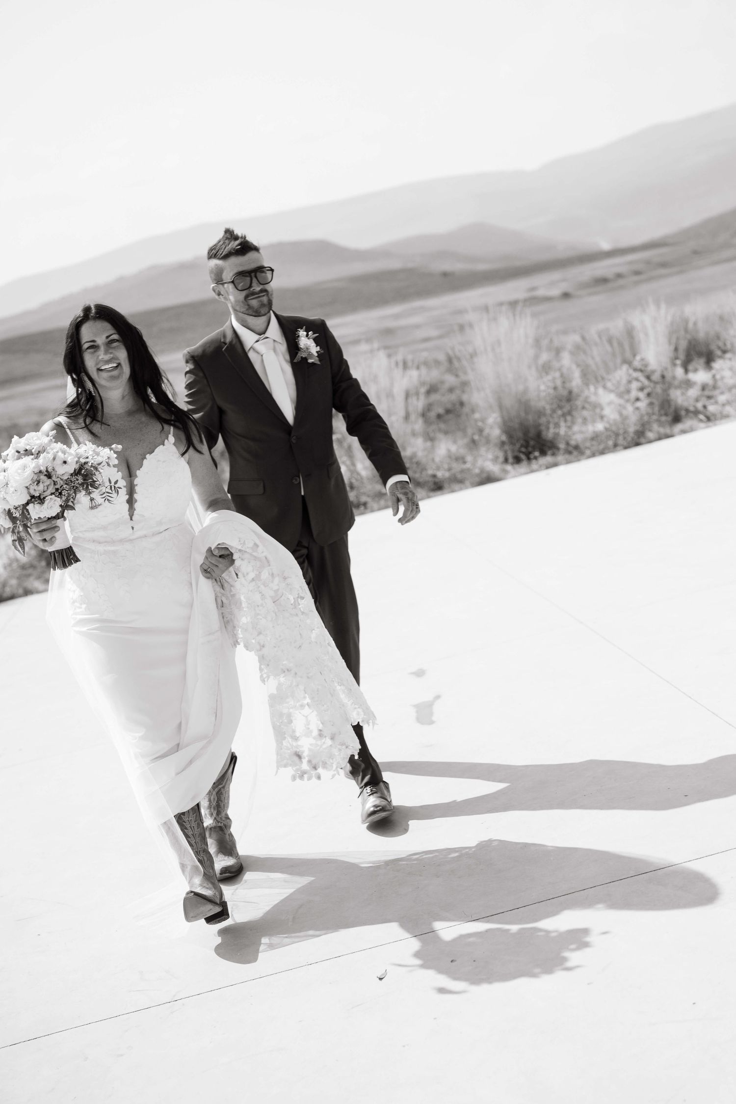4 Eagle Ranch Vail Wedding Venue - Black and white photo of a smiling bride and groom walking together outdoors on their wedding day.
