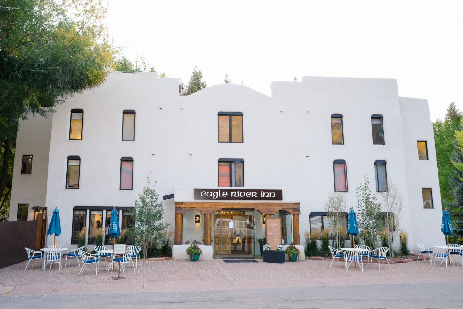A series of white stucco buildings with blue accents and outdoor seating areas at a desert resort property.