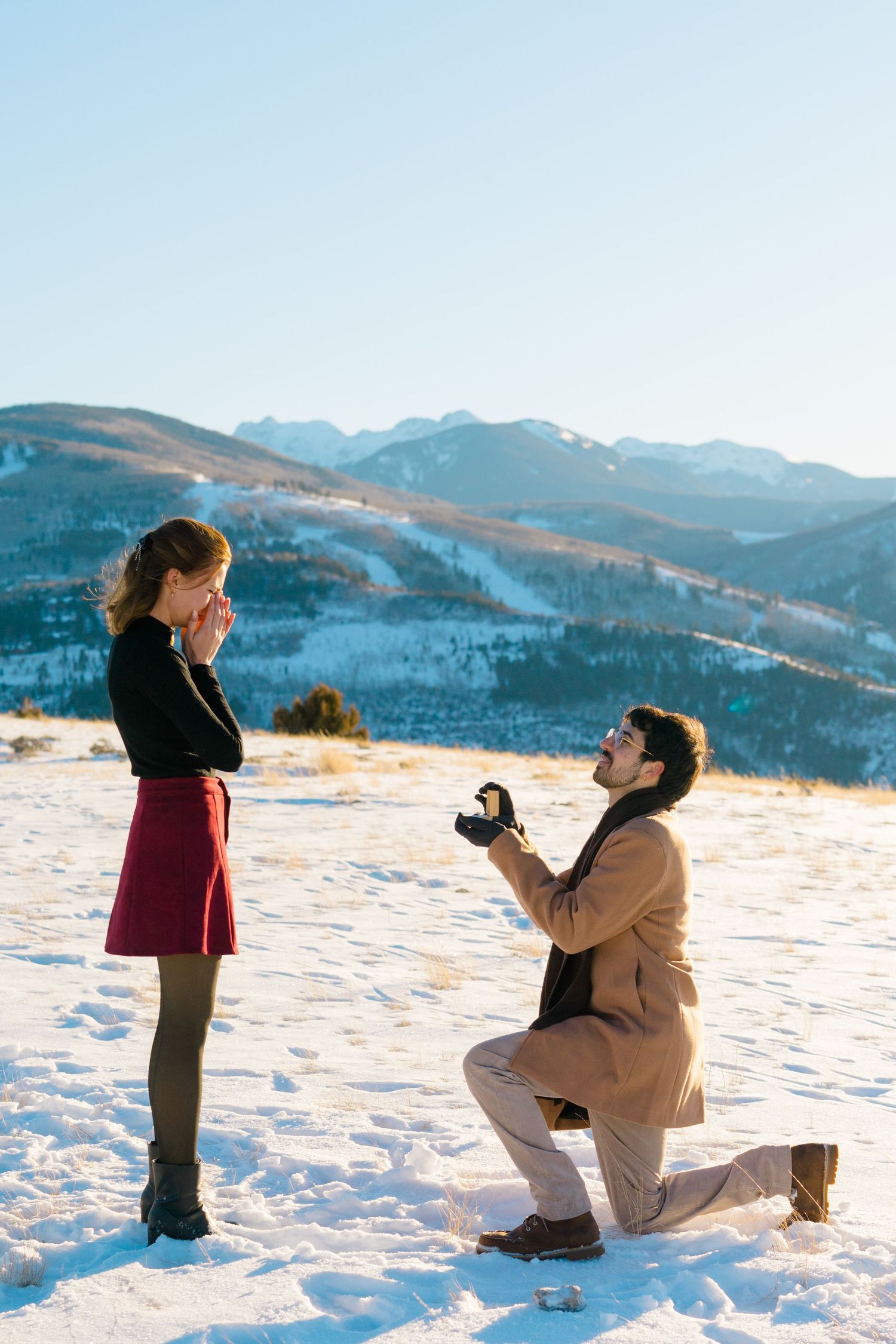 A snowy mountain proposal scene unfolds as a couple shares a special moment against a scenic winter landscape.