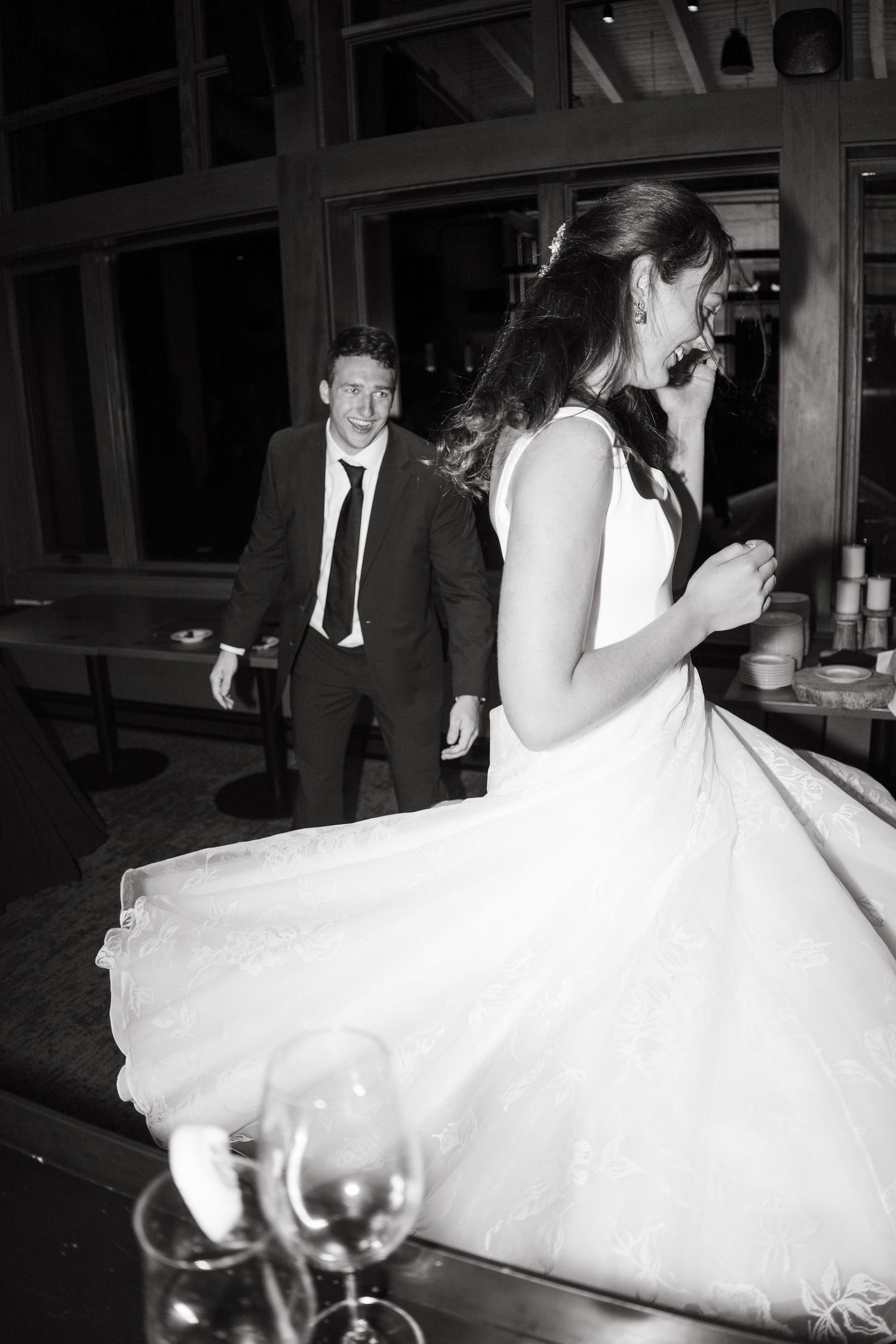 A couple dances and spins in formal wedding attire at an indoor reception venue.