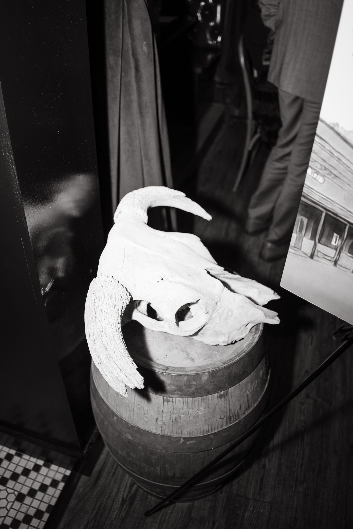 White gloved hands cutting into a wedding cake on wooden surface in dark setting.