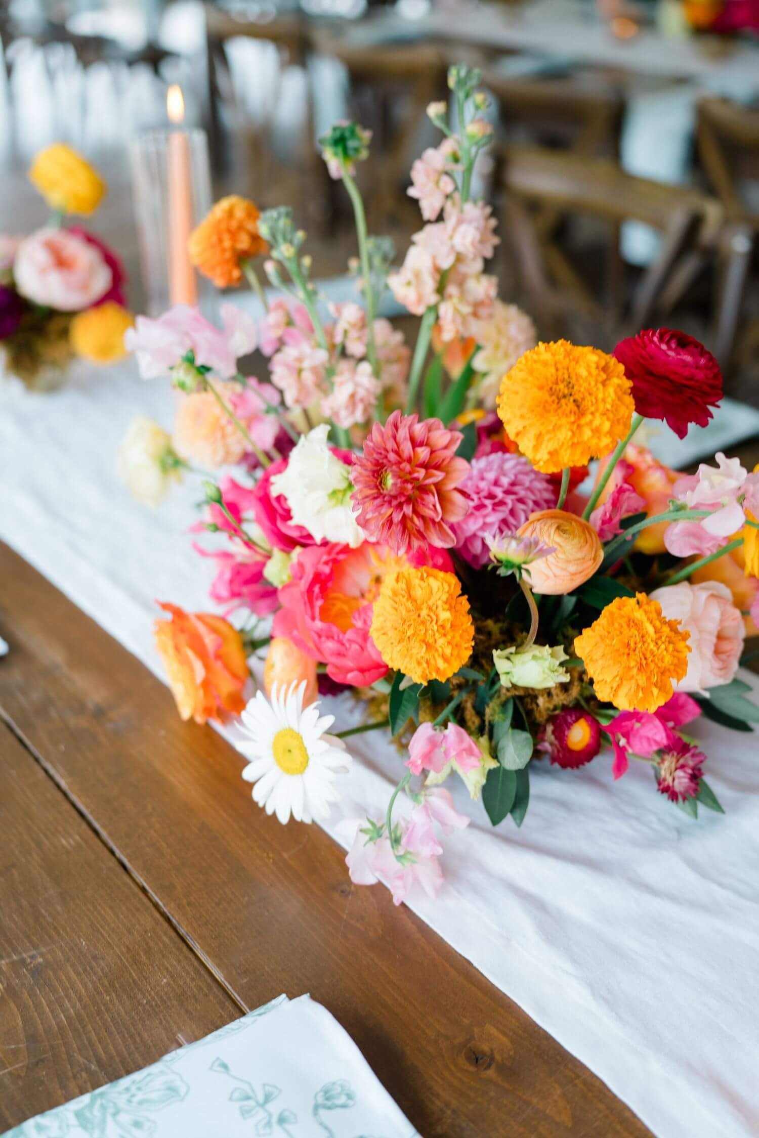 Vibrant floral centerpieces with orange, pink, and white blooms arranged on rustic wooden tables camp hale wedding