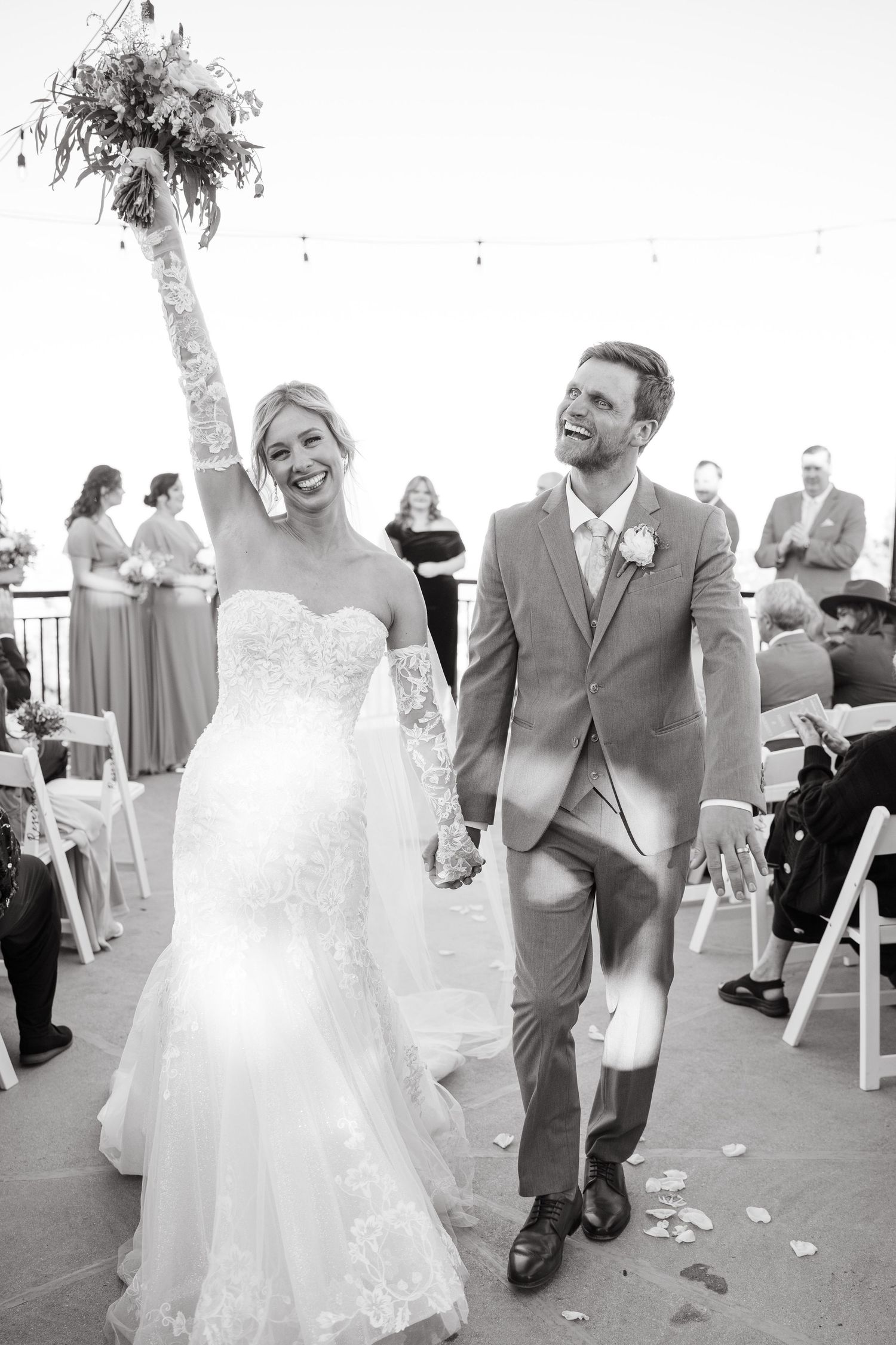 black and white photo of couple walking out of wedding ceremony celebrating