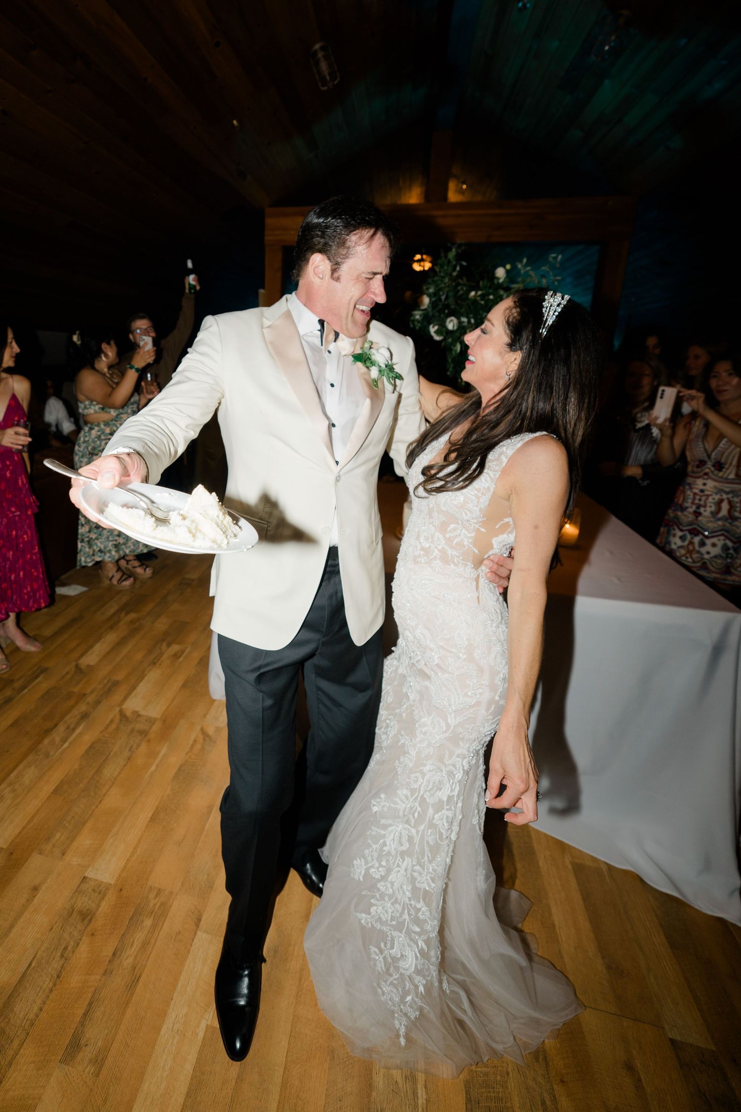 A couple shares a joyful moment dancing together at their wedding reception on a wooden dance floor.