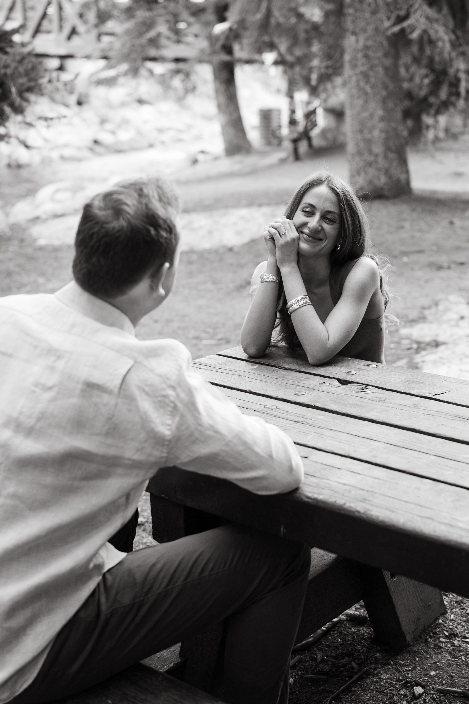 A romantic black and white photo sequence shows a couple sharing sweet moments at a picnic table in a park.