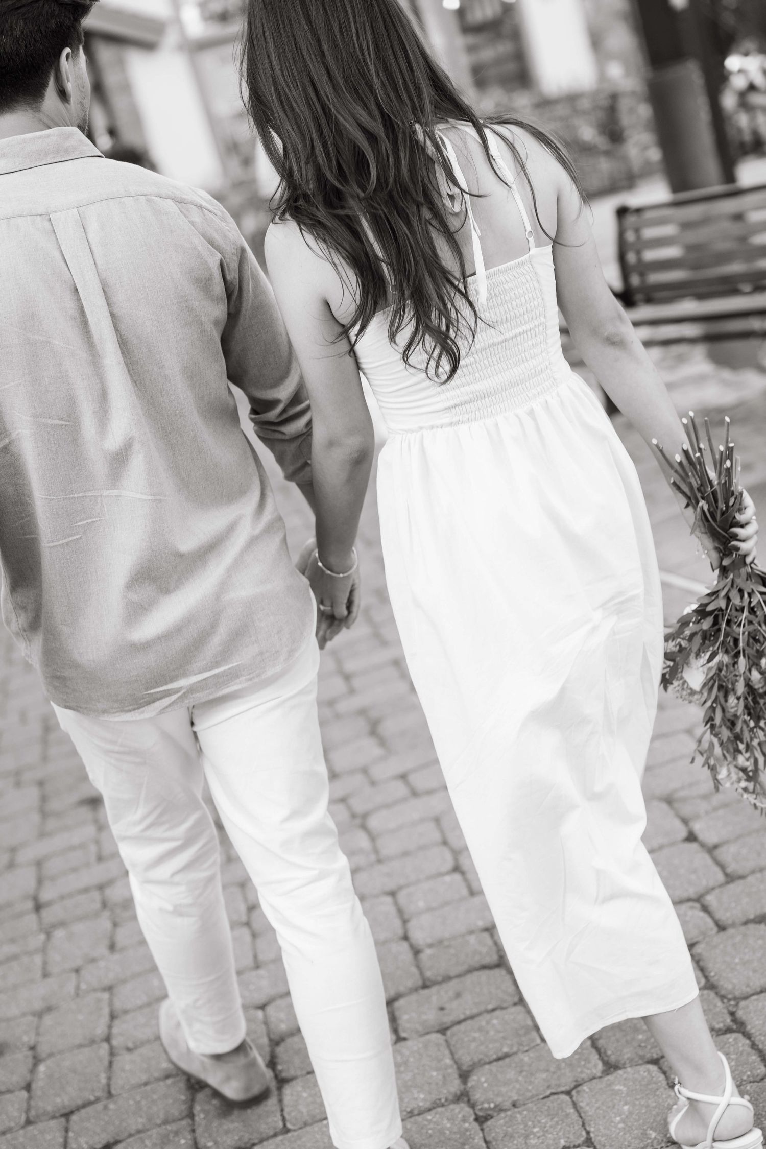 Black and white angled photo showing people in white clothing walking on a brick paved path after vail village proposal