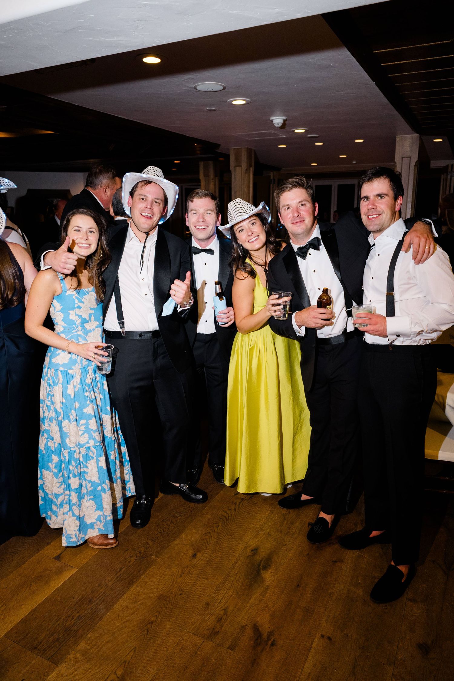 Group of friends in formal attire and cowboy hats posing together at an elegant indoor event.