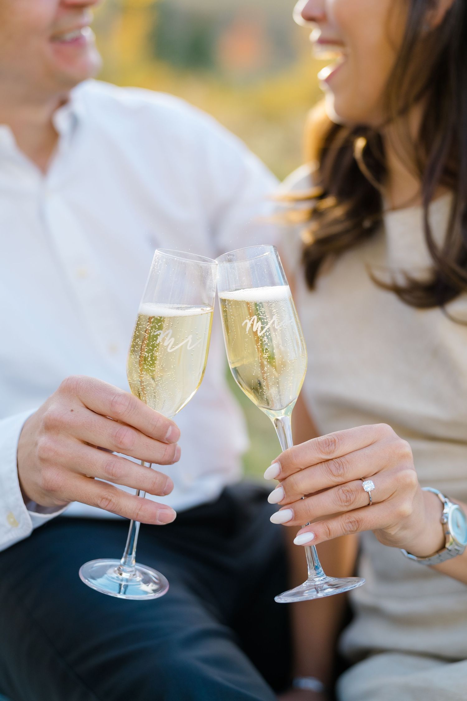 Two champagne glasses clink together in a celebratory toast against a soft blurred background during vail proposal.