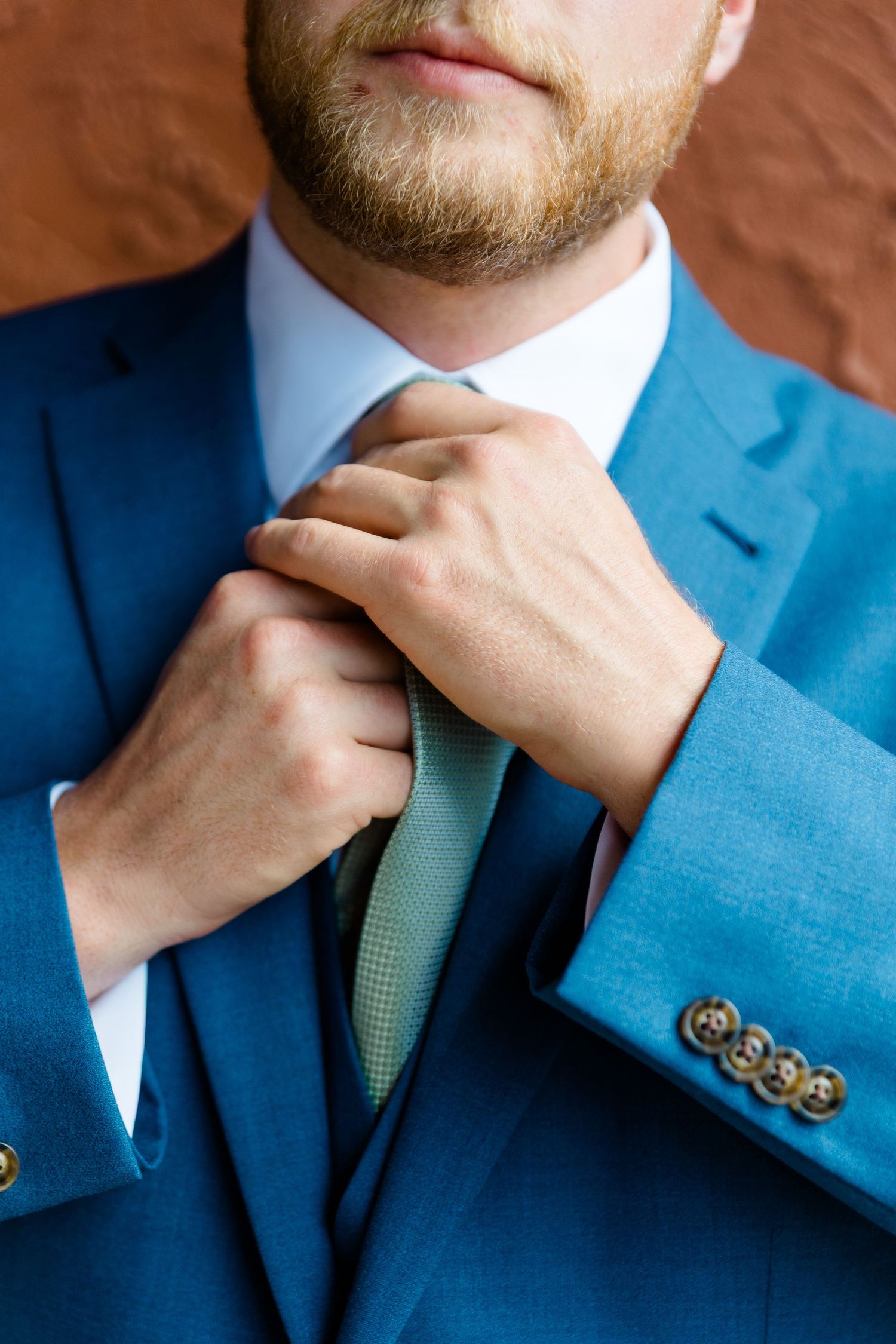 Close-up sequence showing someone adjusting a mint green tie while wearing a bright blue suit jacket during vail wedding preparation.
