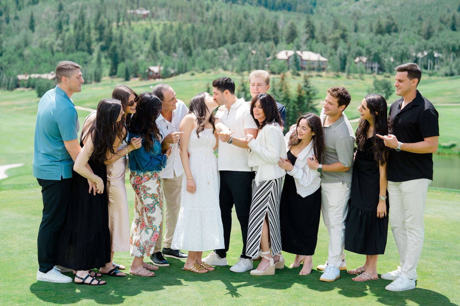 Wedding guests seated in rows on a grassy hillside with mountain views in the background.