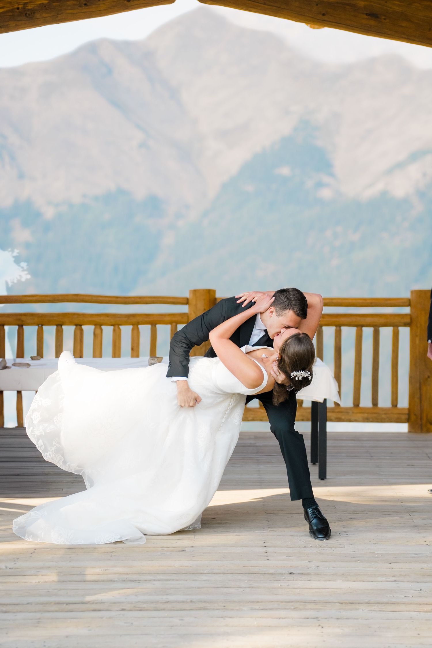 A couple in wedding attire shares a romantic dip pose on a scenic mountain deck during their wedding photoshoot at copper mountain.