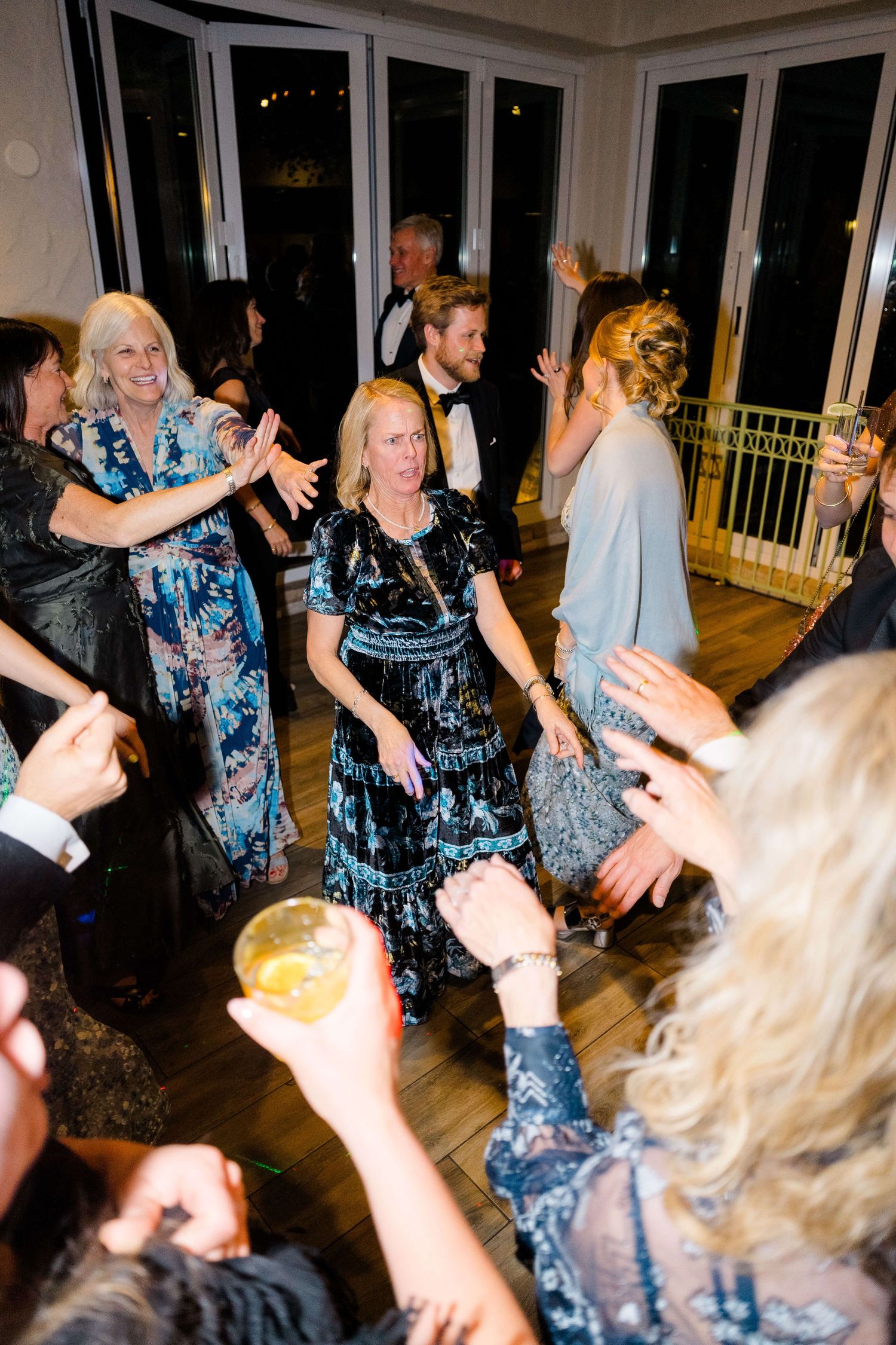 Guests dancing and celebrating at an elegant indoor wedding reception party in formal attire.